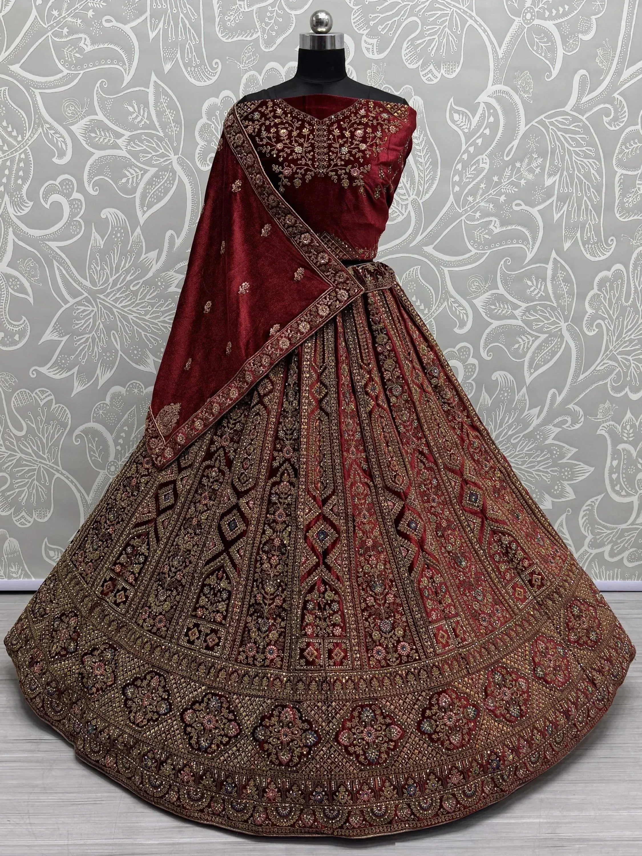 Maroon velvet designer lehenga choli with heavy gold embroidery and matching dupatta, perfect for weddings
