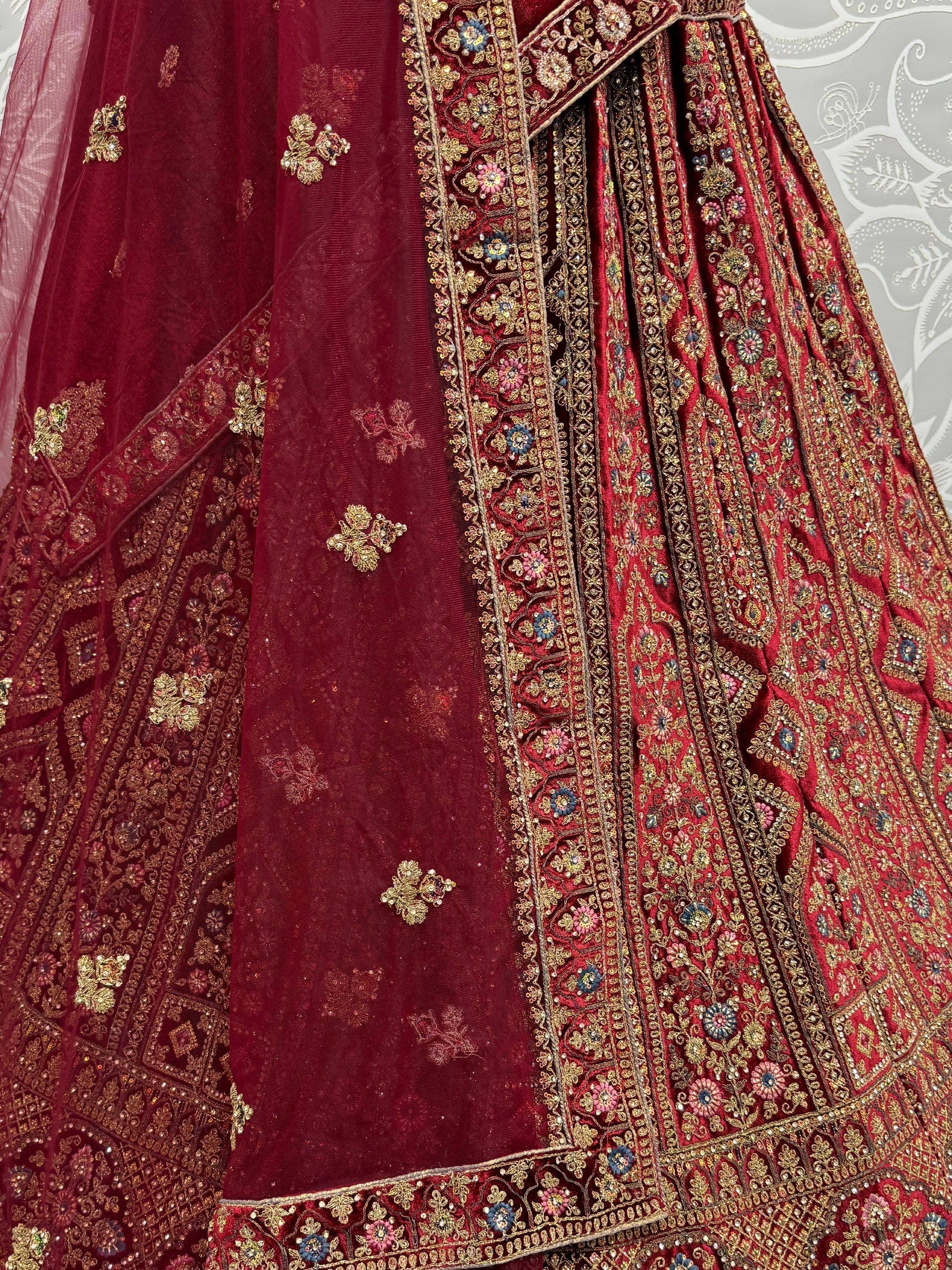 Luxury maroon lehenga choli with intricate gold embroidery and floral motifs, perfect for Indian weddings.
