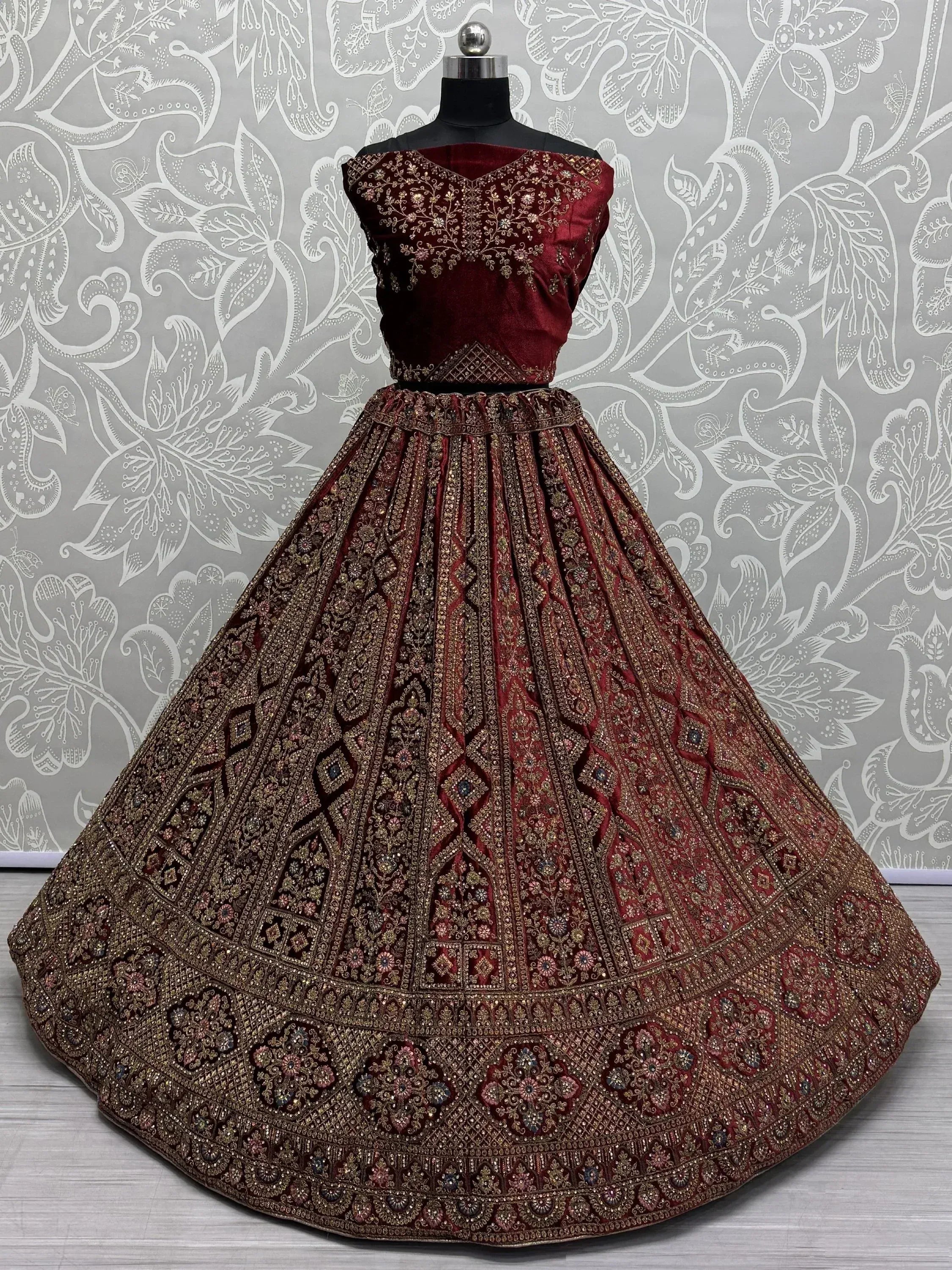 Maroon velvet designer lehenga choli with heavy gold embroidery, perfect for Indian weddings and festive occasions.