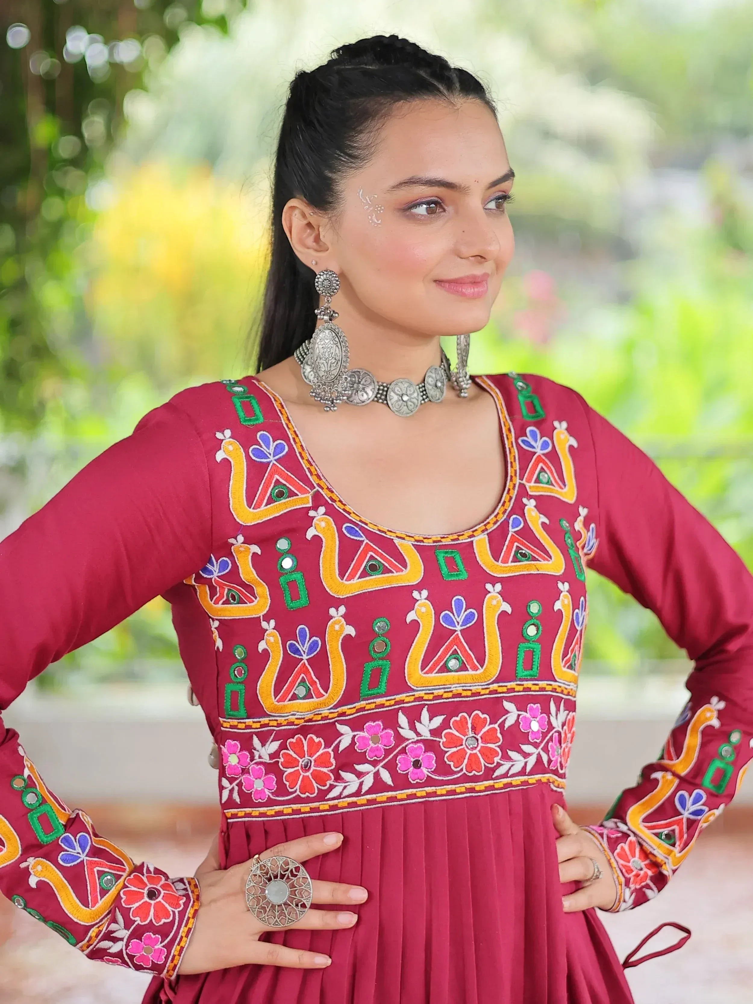 Maroon ethnic gown with colorful peacock embroidery and floral patterns, paired with silver jewelry