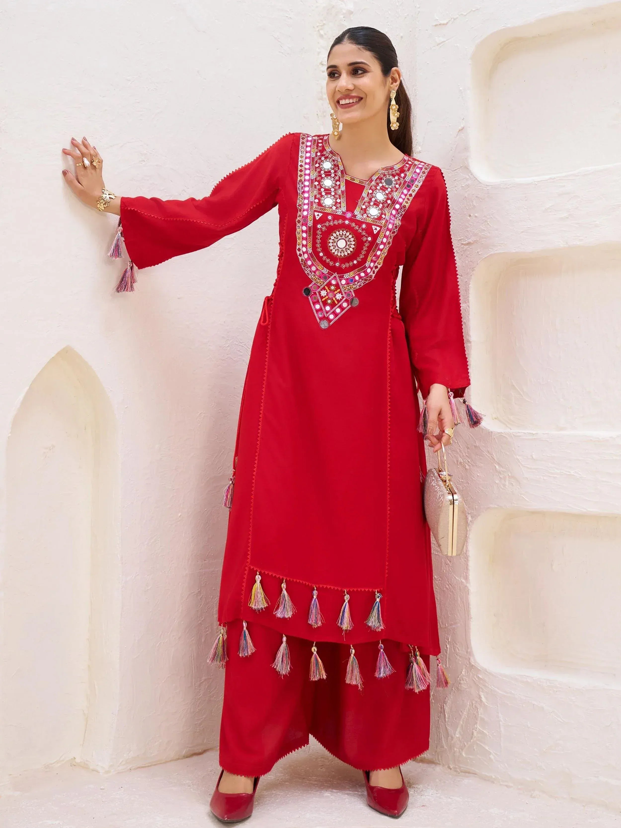 Red ethnic kurta with mirror work and tassels, paired with palazzo pants for festive occasions