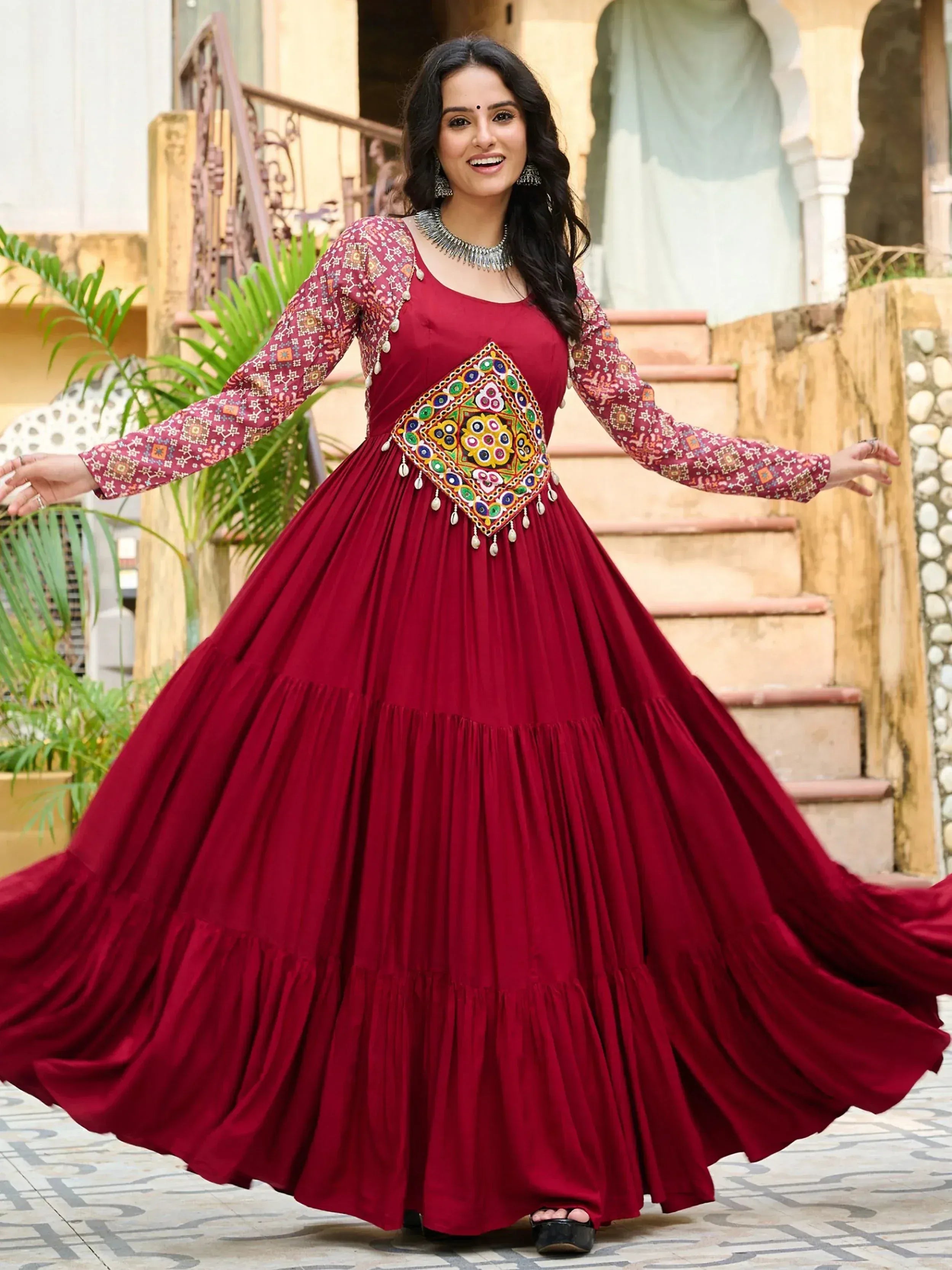 Woman in maroon ethnic gown with colorful embroidery and mirror work, perfect for Indian celebrations