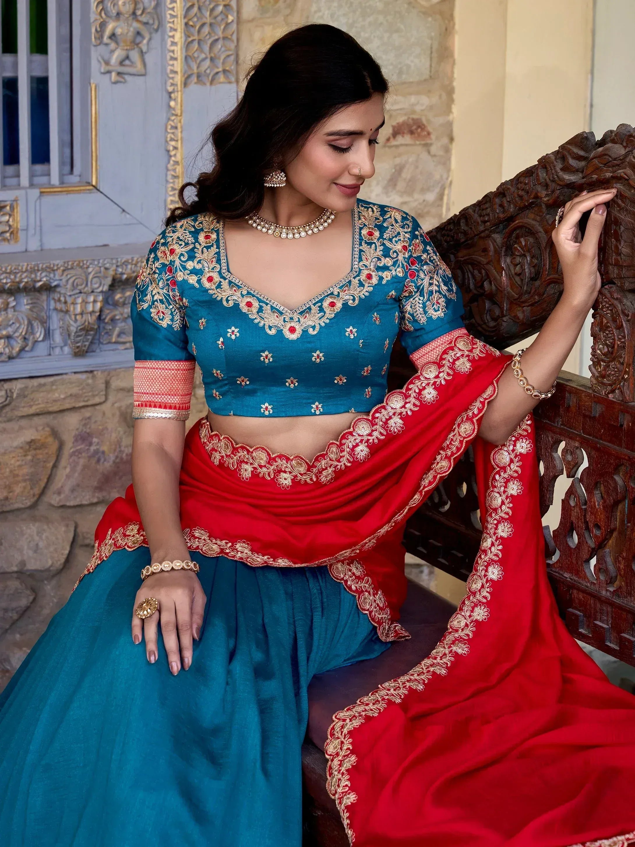 Teal and red embroidered lehenga choli with gold detailing, perfect for Indian ethnic wear occasions.