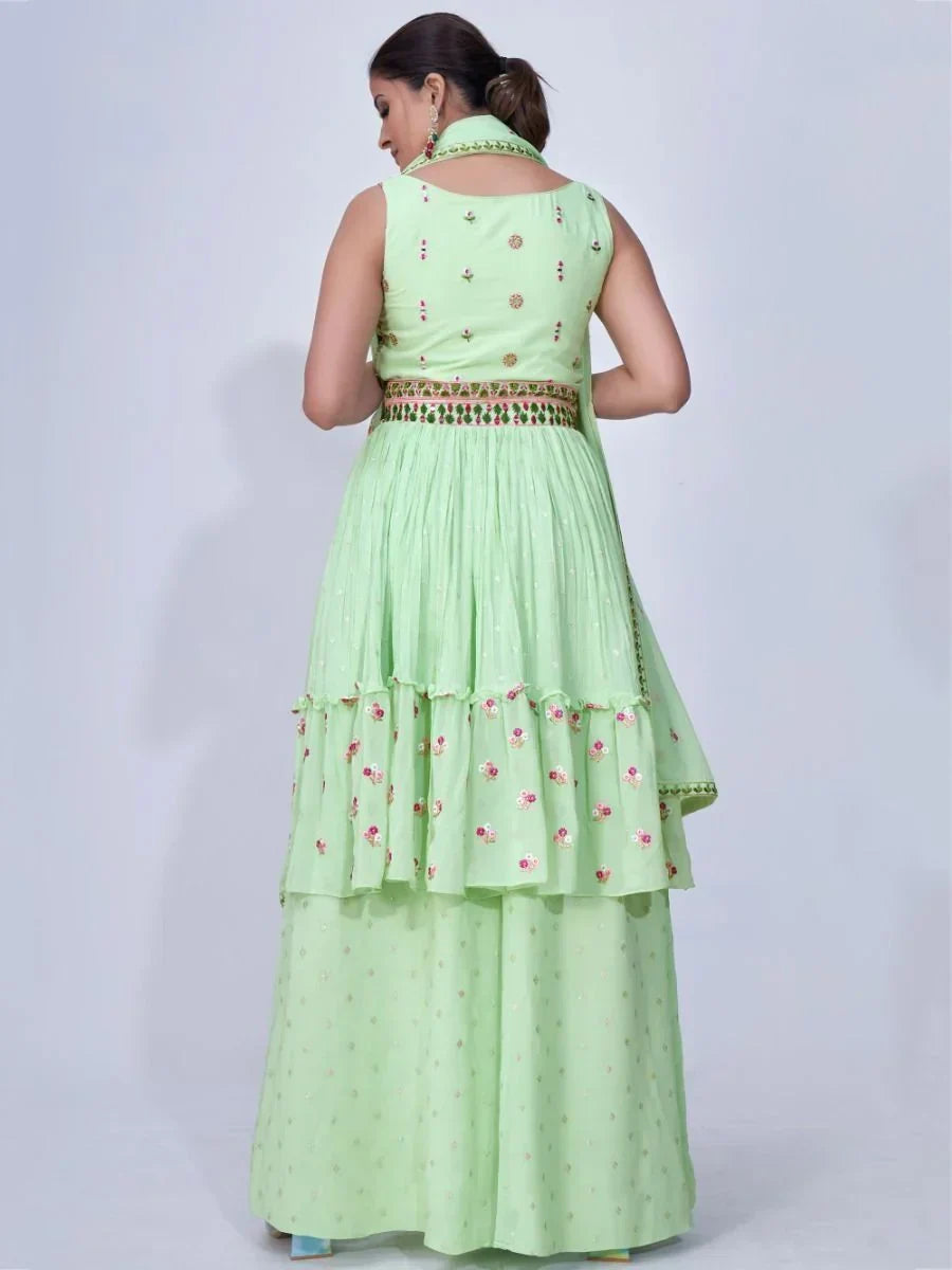 Woman wearing pastel green designer lehenga choli with floral embroidery, back view
