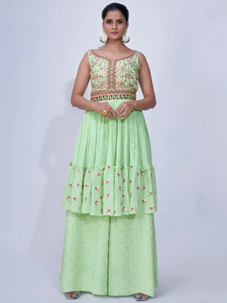 Woman wearing light green embroidered ethnic gown with flared palazzo pants, floral details.