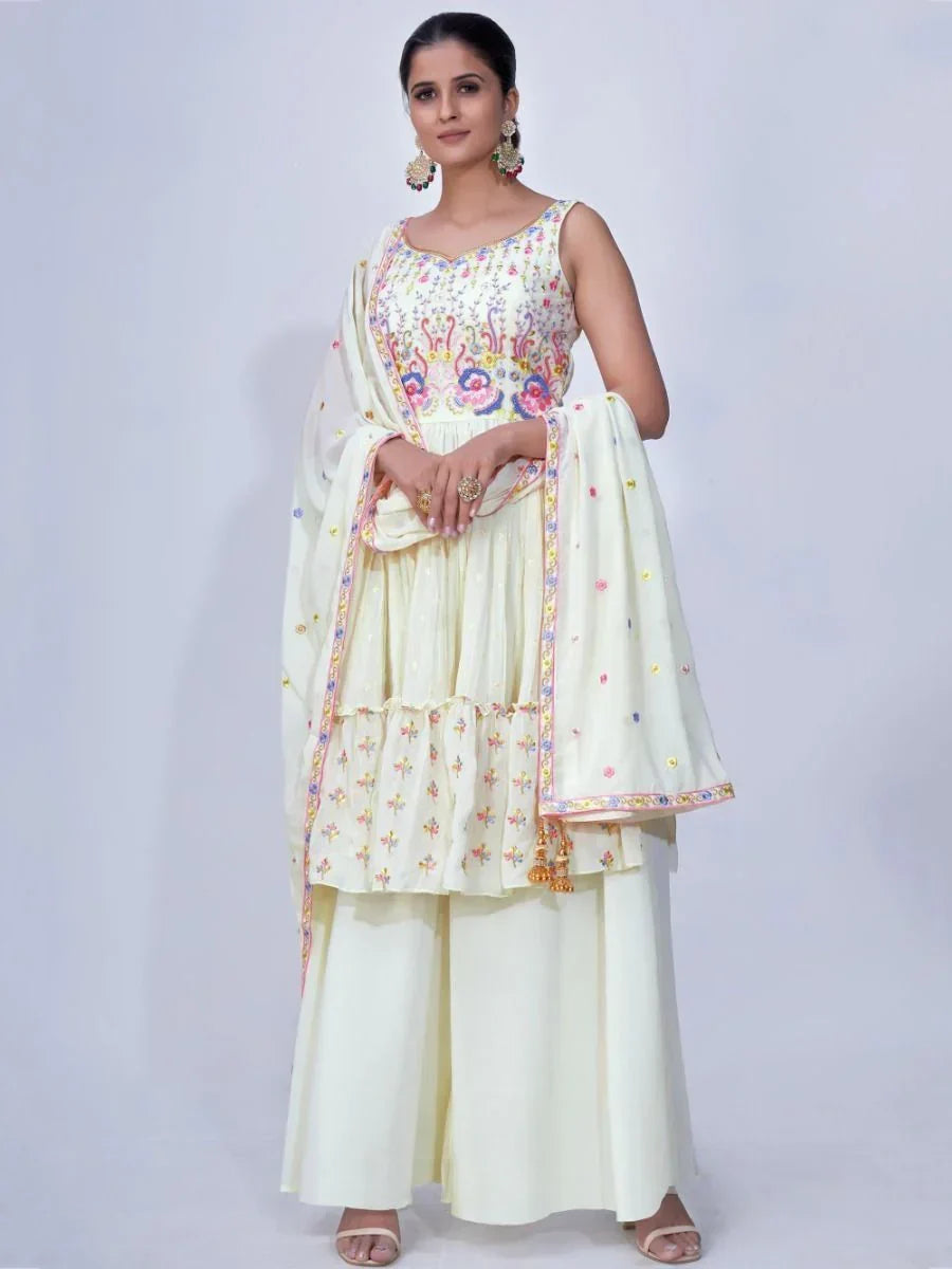 Woman wearing a cream ethnic sharara suit with colorful embroidery and matching dupatta