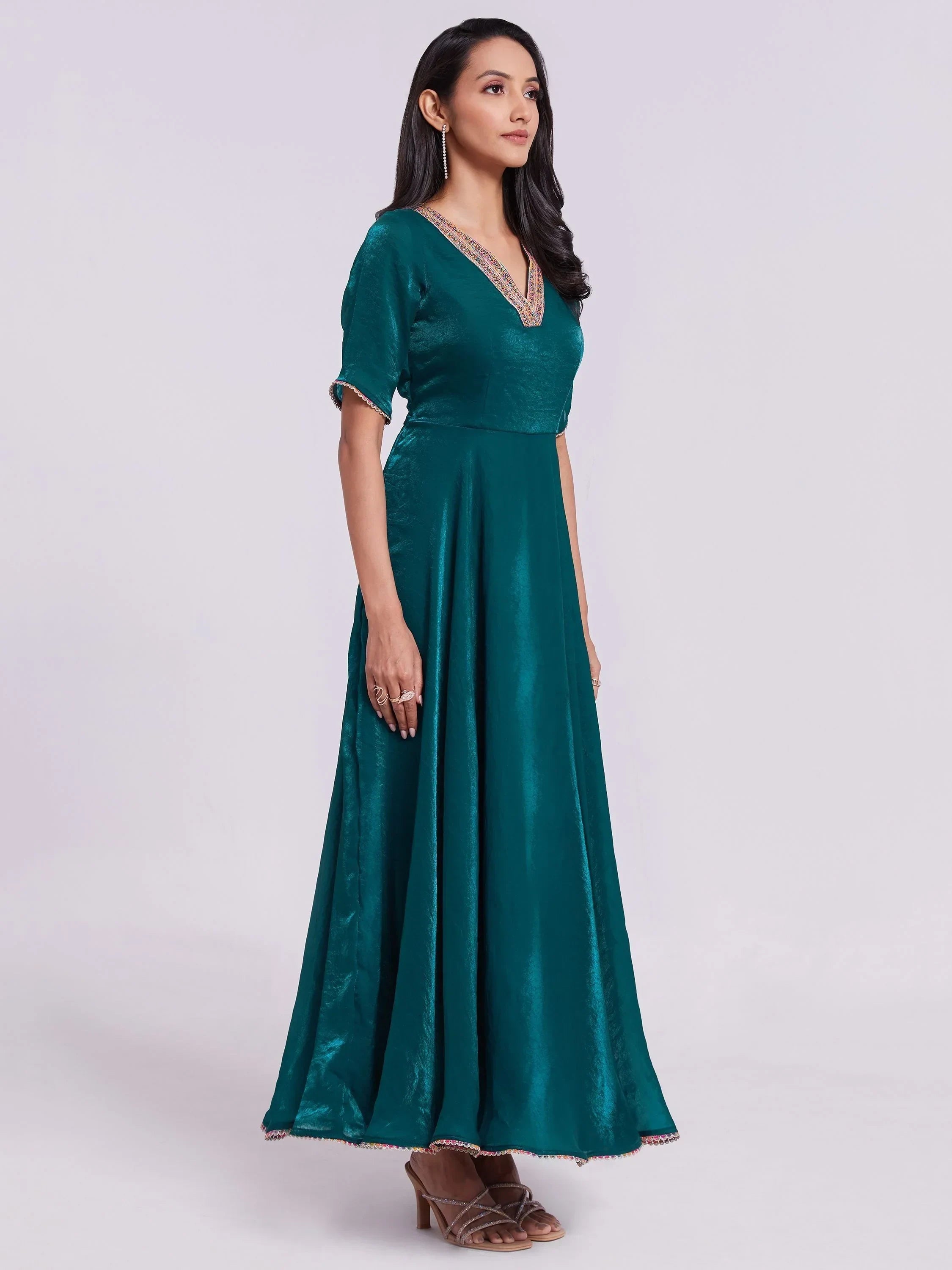 Woman in teal ethnic gown with V-neck and half sleeves, standing in studio