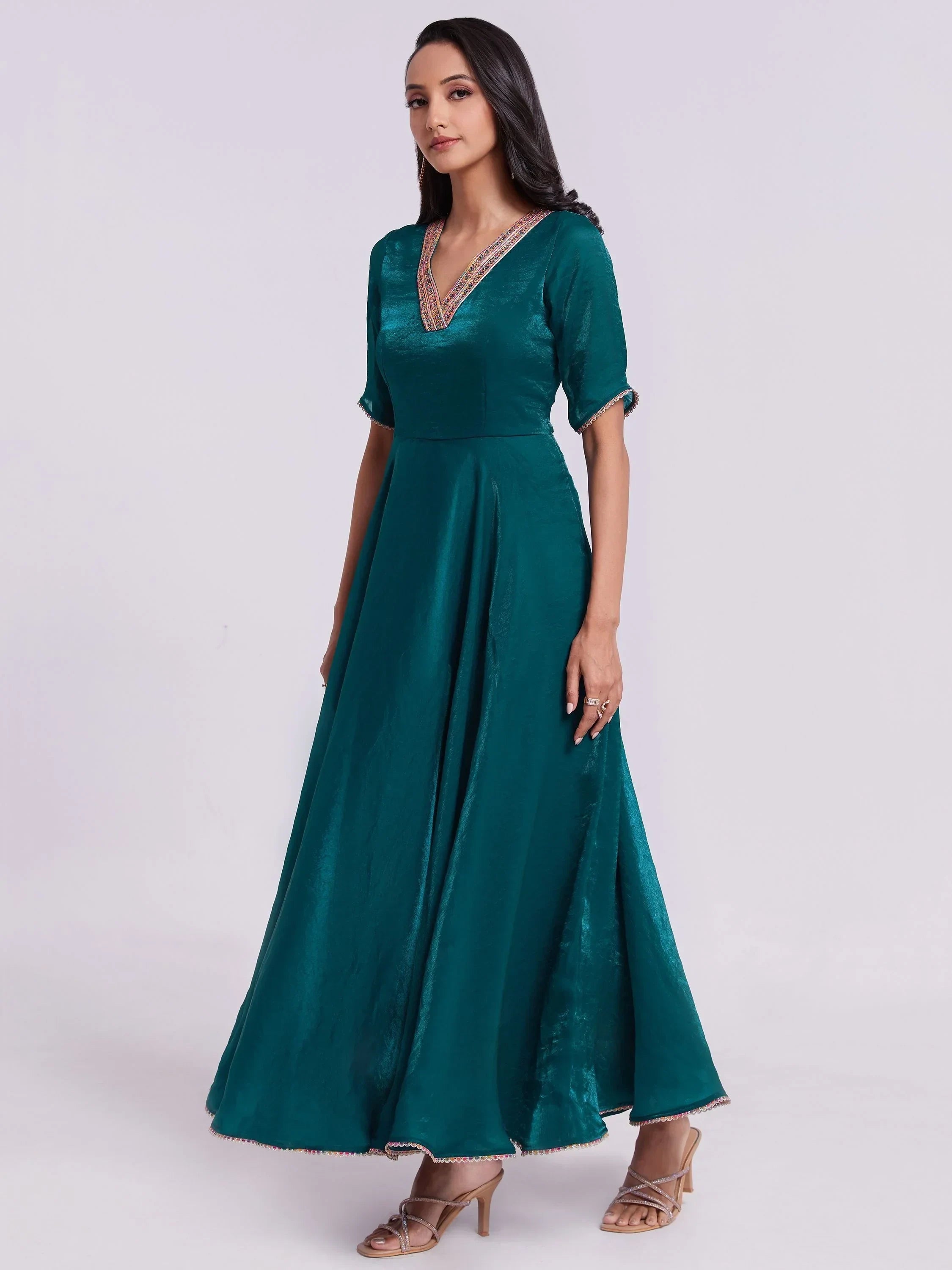 Woman wearing teal silk ethnic gown with half sleeves and embroidered neckline