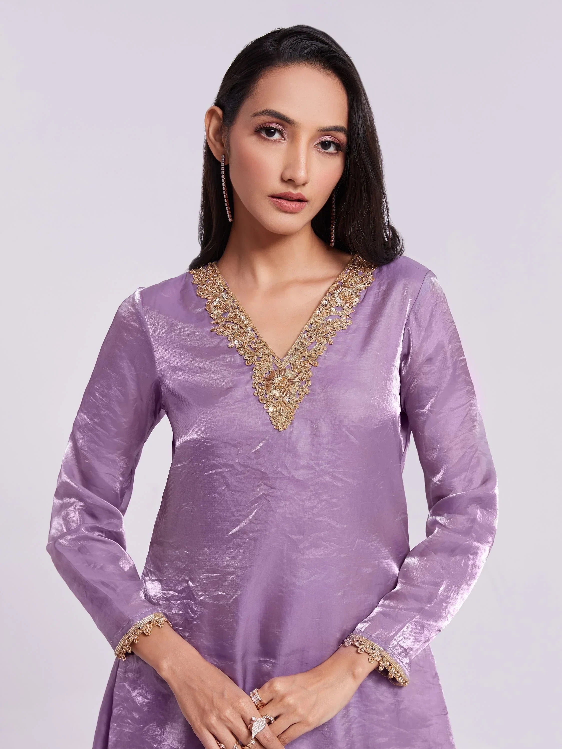 Woman in lavender ethnic kurti with gold embroidery, long sleeves, and statement earrings