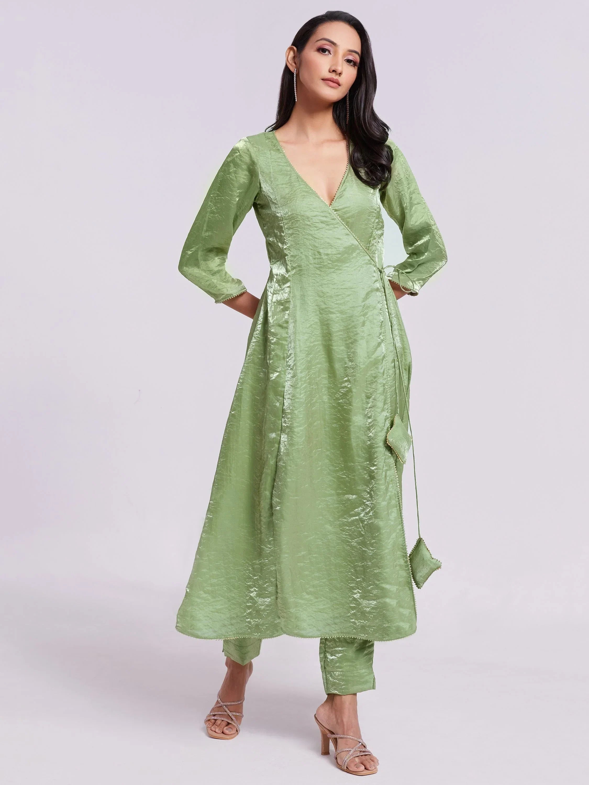 Woman in a light green silk kurta set with V-neck, three-quarter sleeves, and matching pants