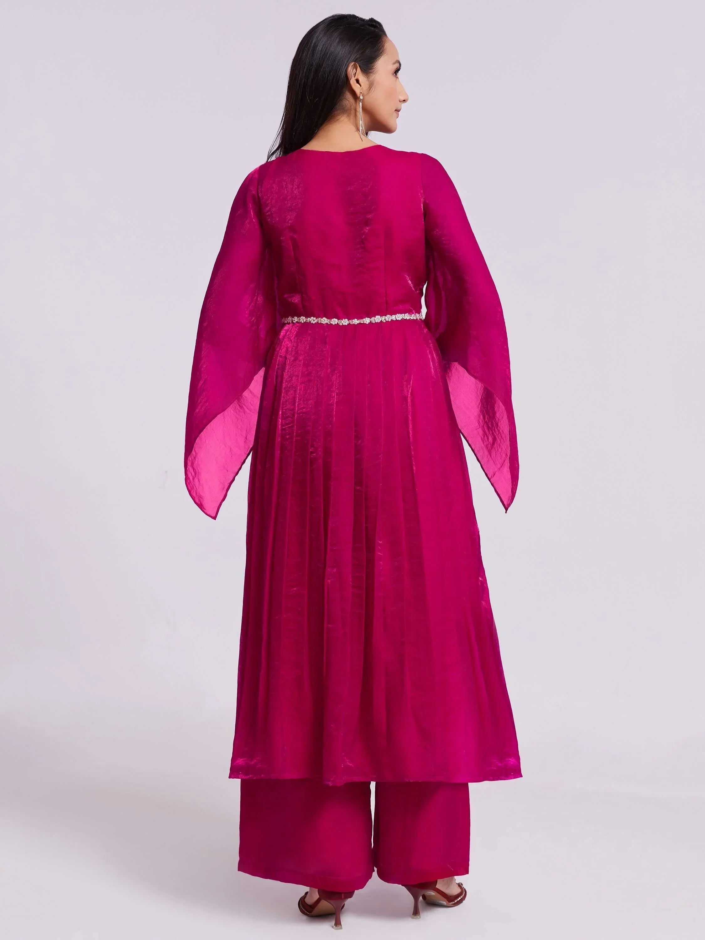 Woman wearing a bright magenta ethnic kurta with palazzo pants, back view