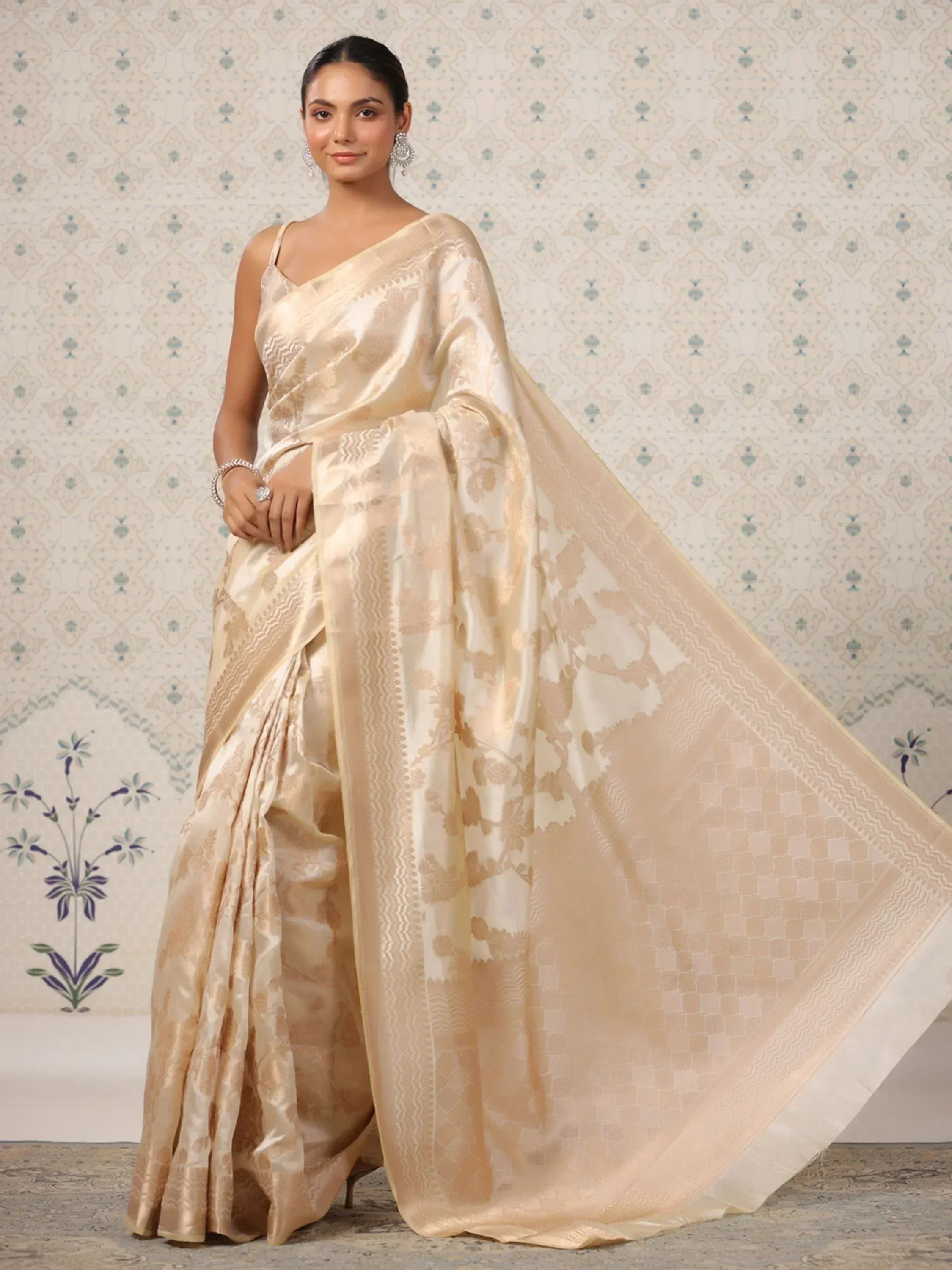 Elegant beige designer saree with floral motifs and intricate border, perfect for ethnic occasions.