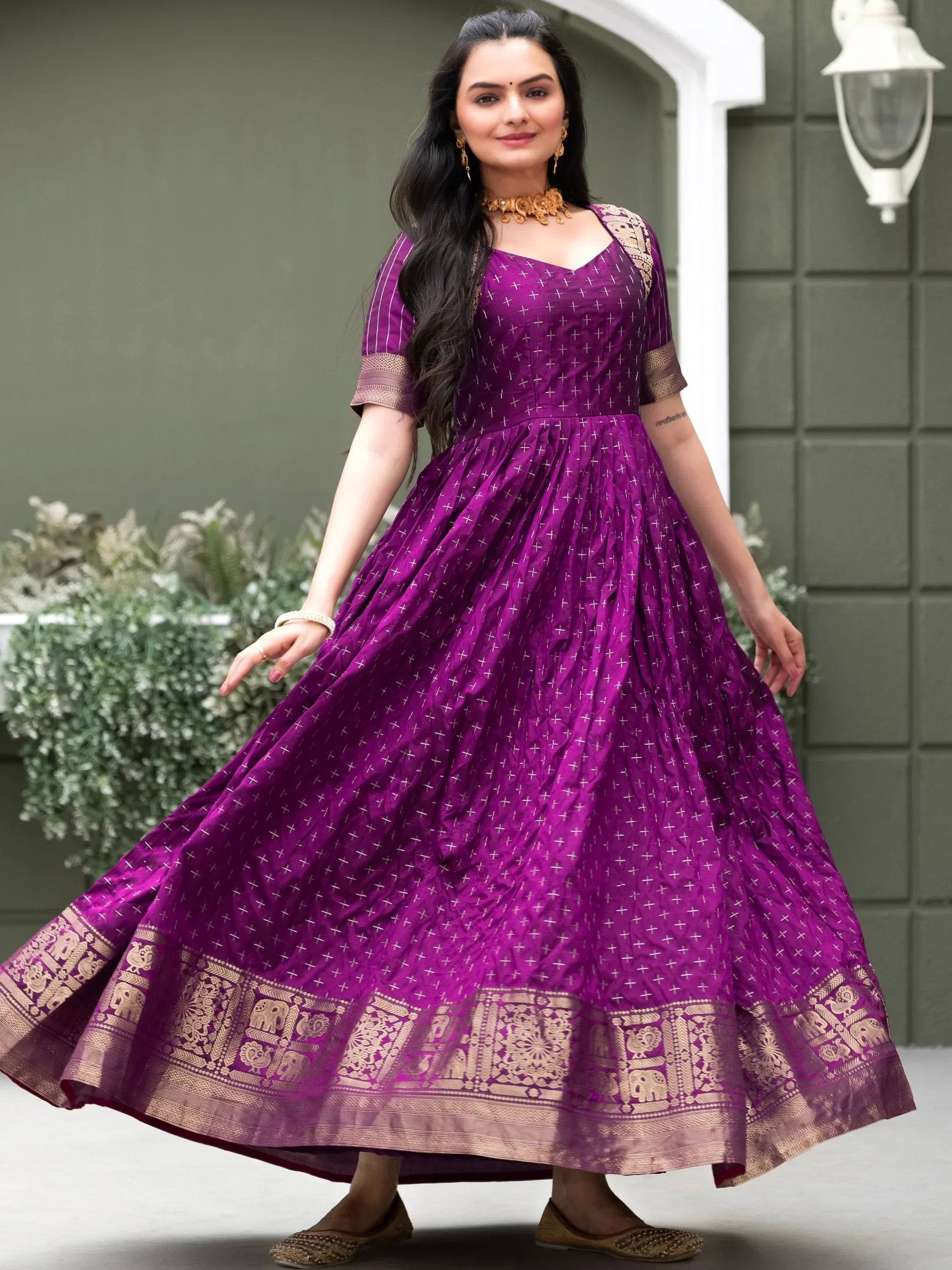 Woman in a purple designer ethnic gown with gold zari border and traditional jewelry
