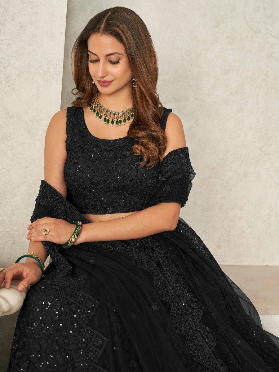 Black sequined lehenga choli with cold shoulder blouse, paired with green jewelry for ethnic wear