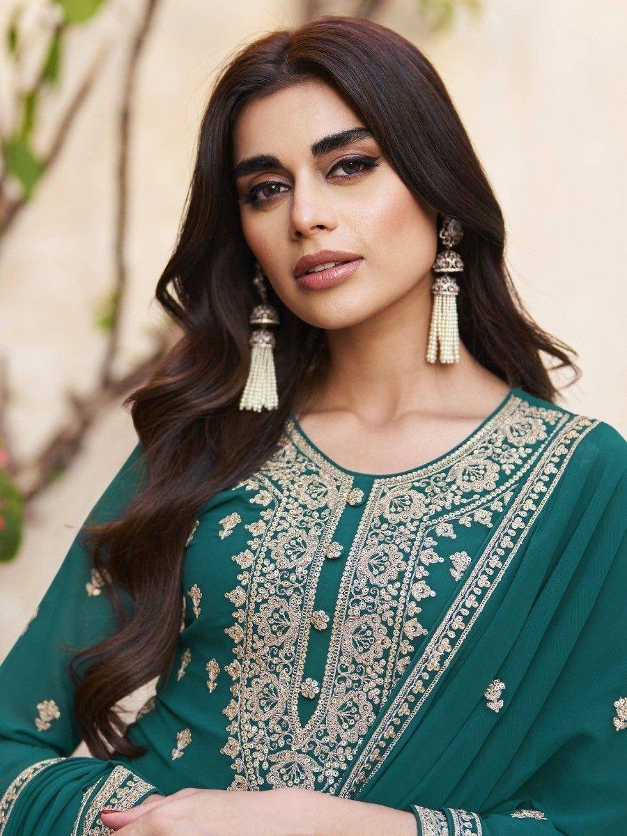 Emerald green embroidered ethnic kurti with gold detailing, paired with tassel earrings for festive occasions.