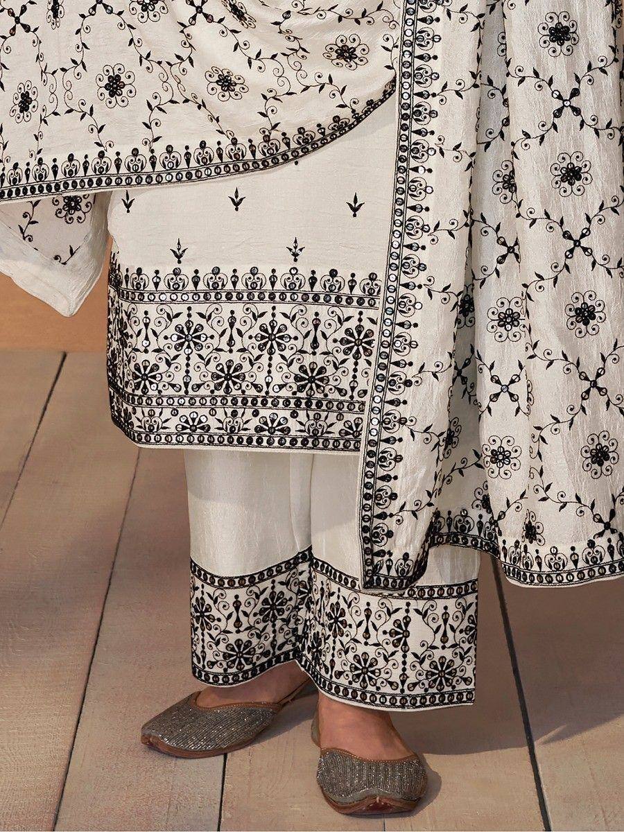 White ethnic salwar kameez with black floral embroidery, paired with embellished flats