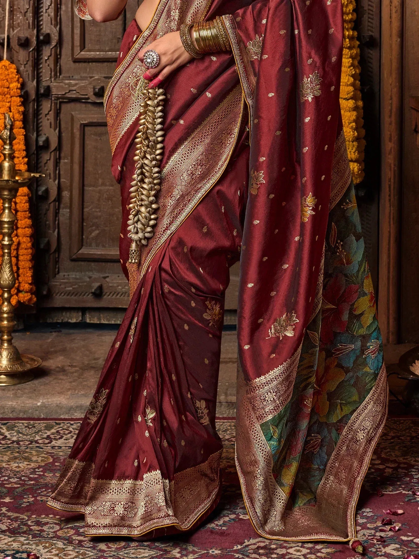 Maroon silk saree with gold floral embroidery and contrasting floral pallu, styled with traditional jewelry