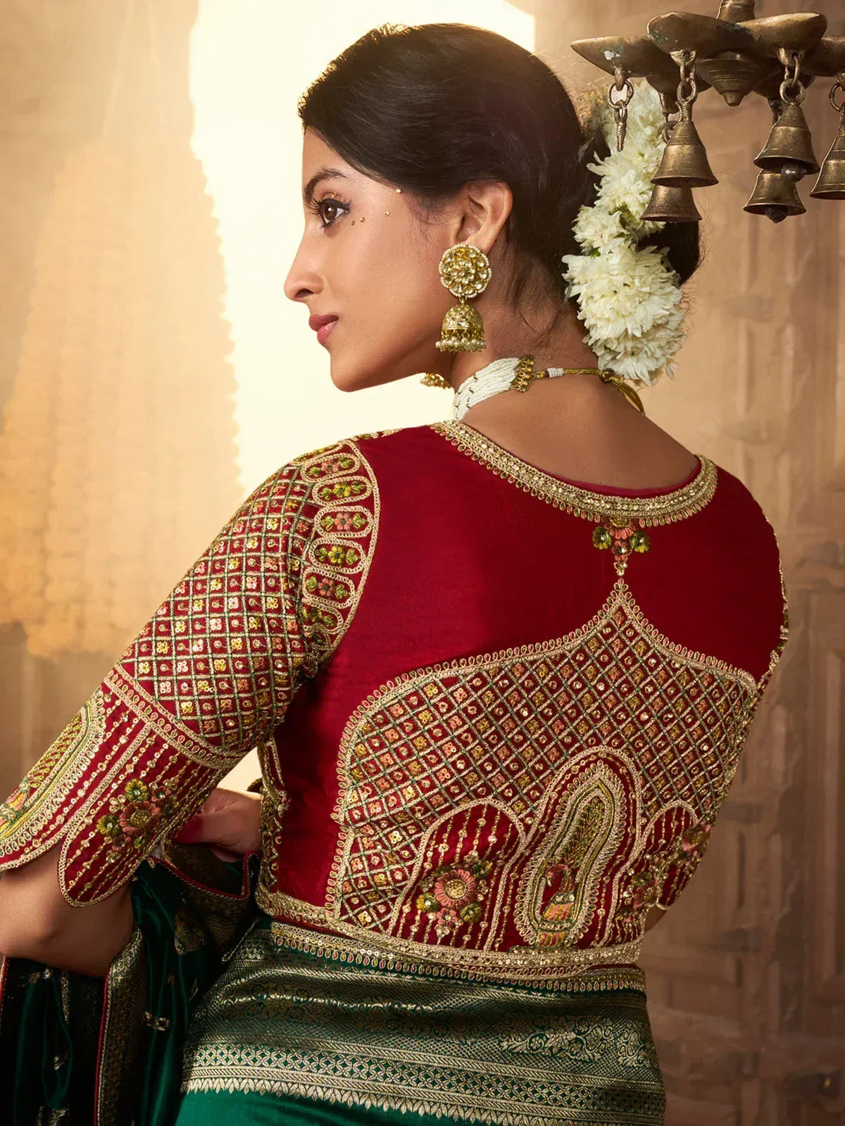 Red and green embroidered Indian ethnic blouse with gold detailing, floral hair accessory, and traditional jewelry