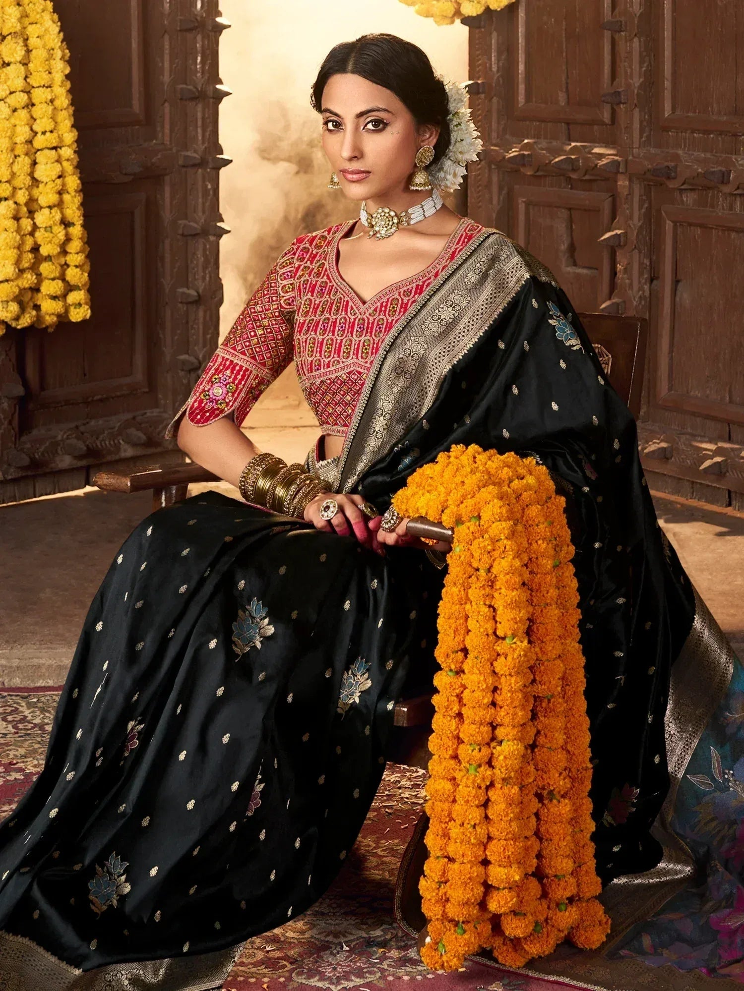 Woman in black embroidered saree with red blouse, floral garlands, traditional Indian ethnic wear