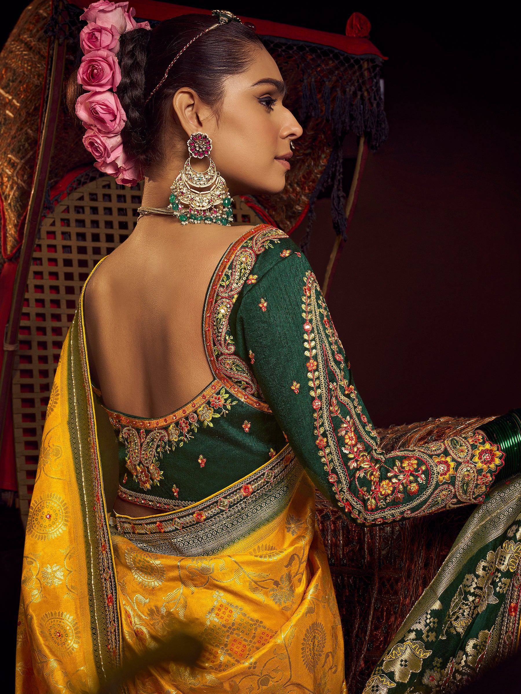 Woman in green embroidered blouse and yellow saree with floral hair accessory and traditional jewelry