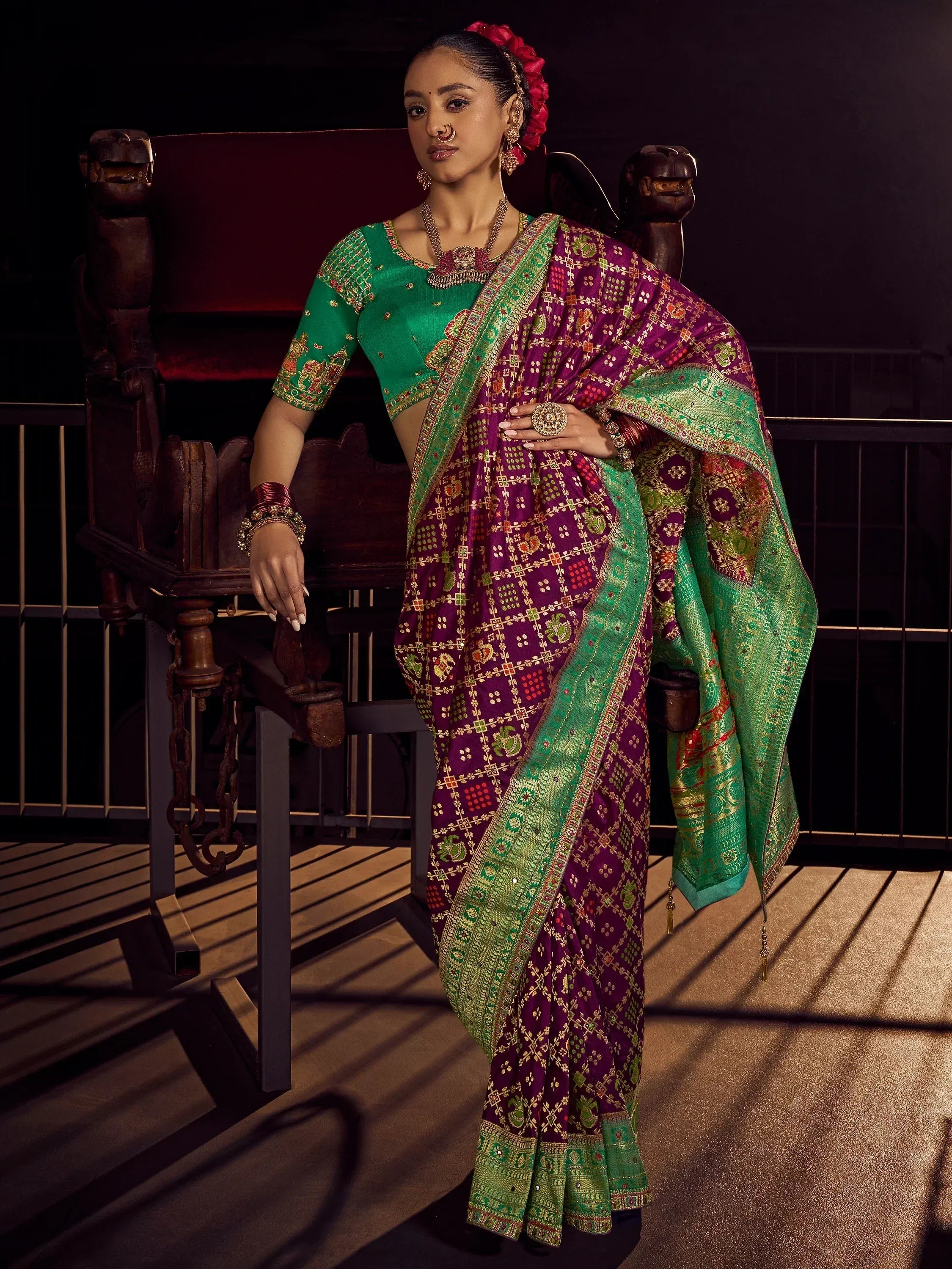 Elegant purple and green designer saree with intricate embroidery, paired with matching blouse and traditional jewelry.