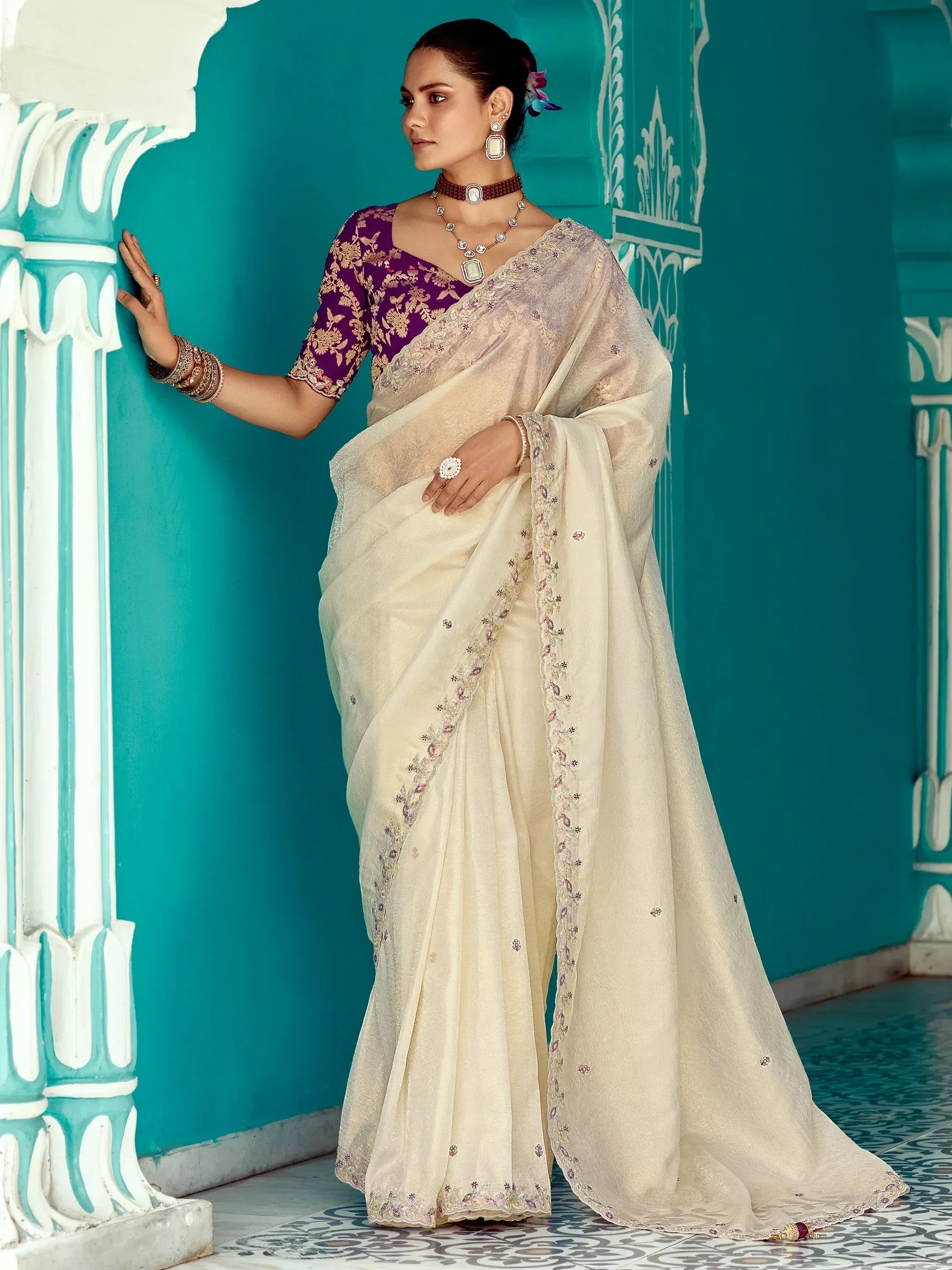 Elegant cream saree with purple embroidered blouse, perfect for Indian ethnic occasions and weddings.