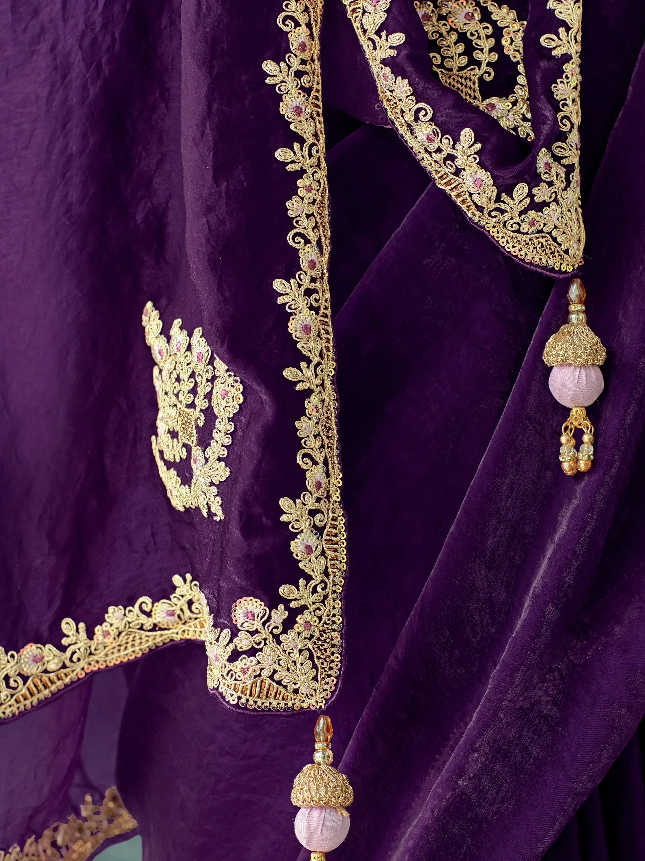 Purple velvet ethnic wear with gold floral embroidery and tassels, perfect for Indian weddings or festive occasions.
