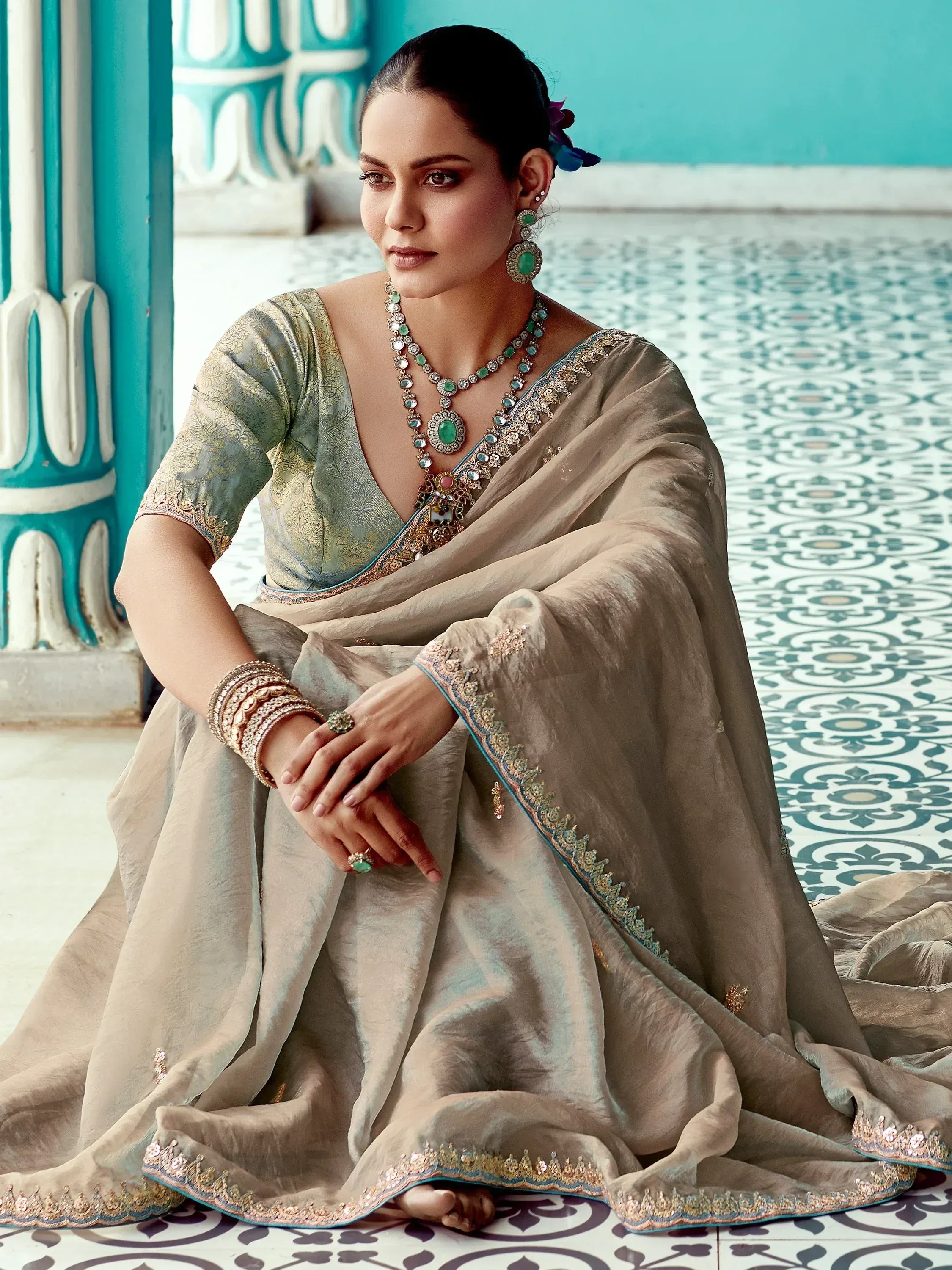 Elegant Indian ethnic saree with gold embroidery, paired with emerald jewelry, perfect for weddings or festive occasions.
