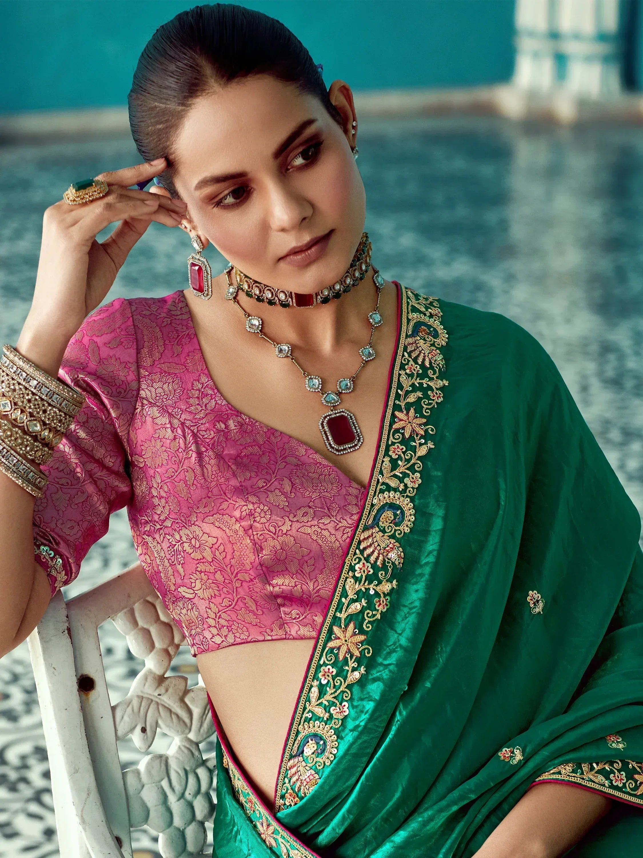 Elegant woman in pink floral blouse and green embroidered saree with traditional jewelry