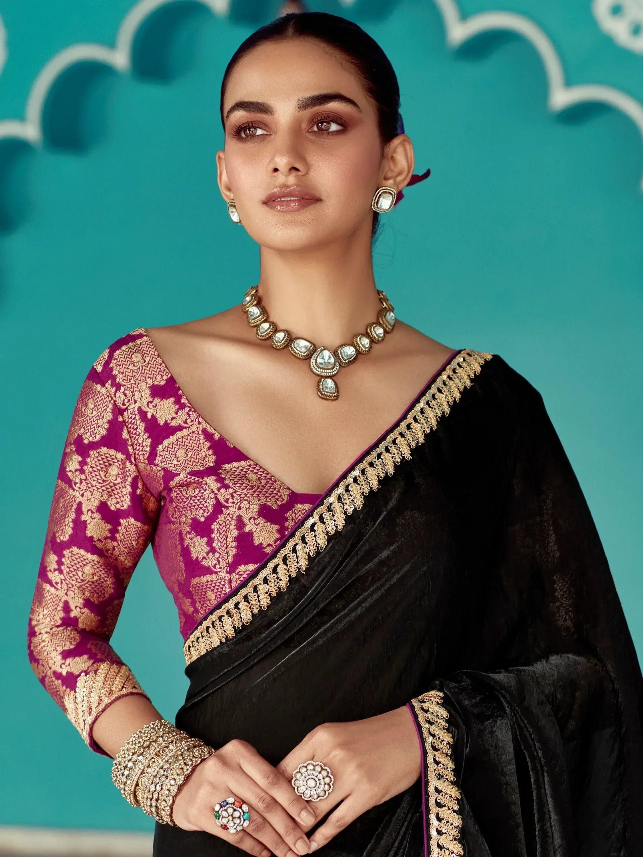 Elegant black velvet saree with gold embroidery, paired with a magenta blouse and traditional jewelry for Indian ethnic wear.