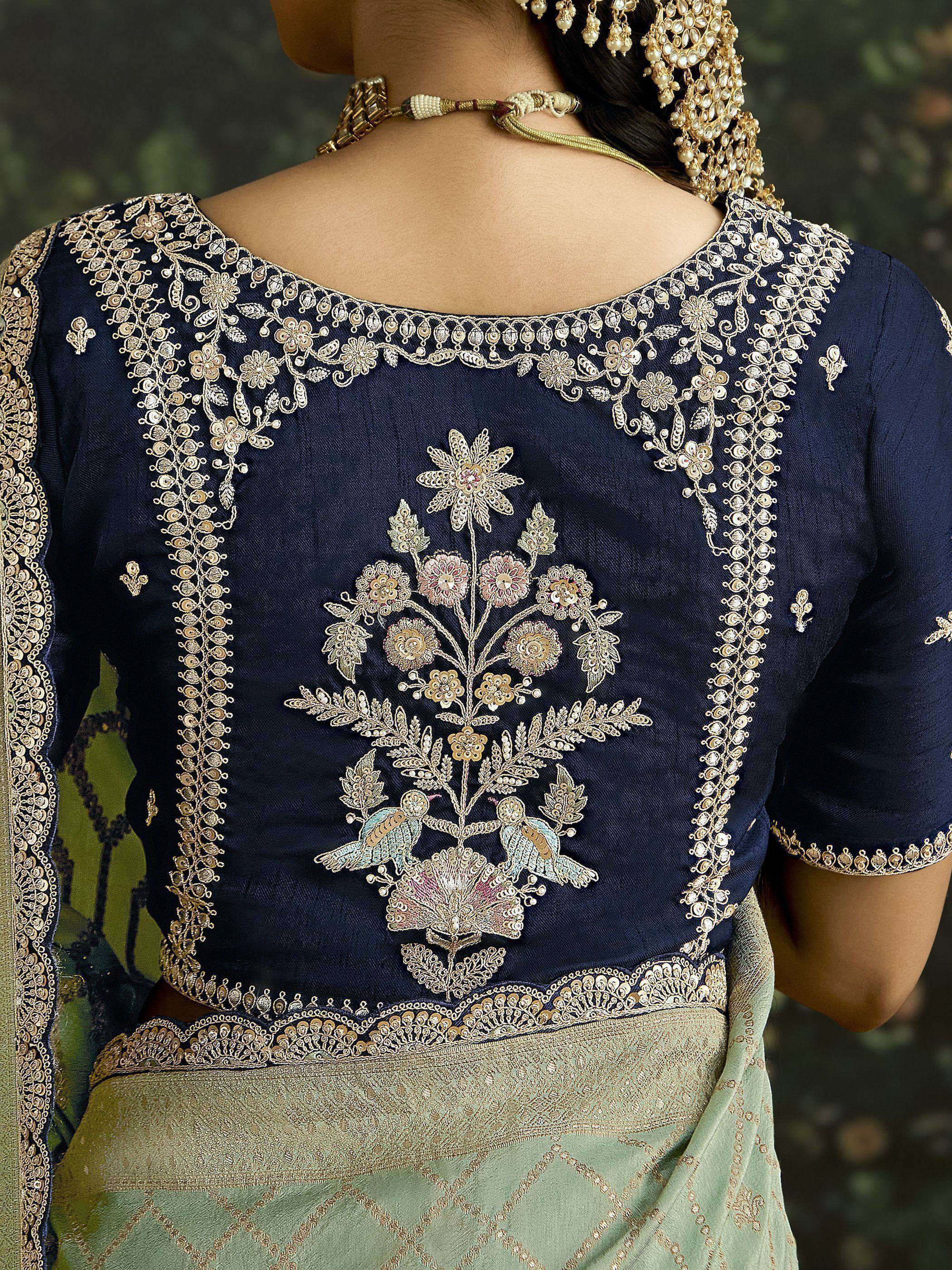 Navy blue designer saree blouse with intricate gold floral embroidery and bird motifs, paired with a green saree.