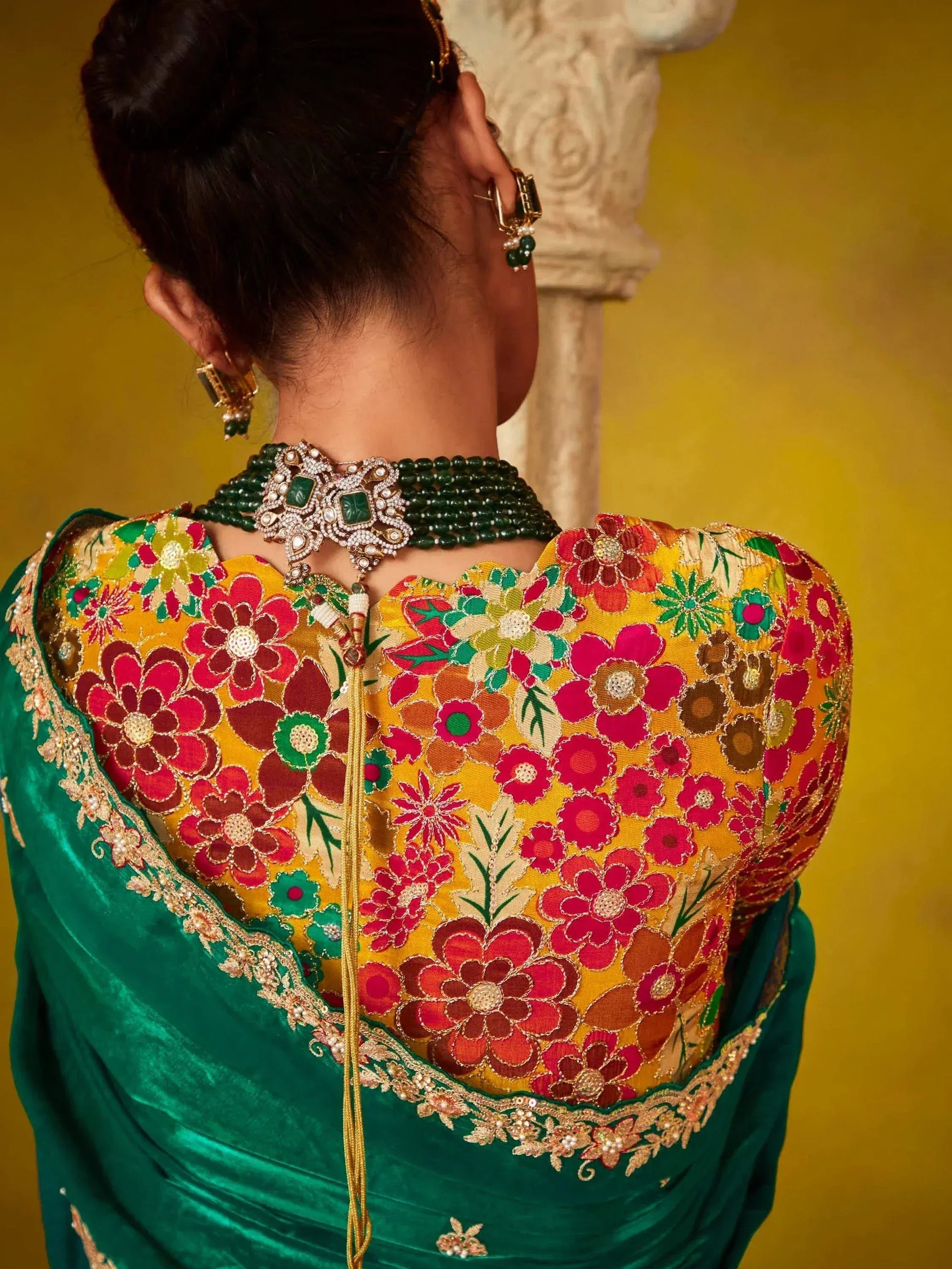 Back view of woman in vibrant floral embroidered lehenga choli with green velvet dupatta and traditional jewelry