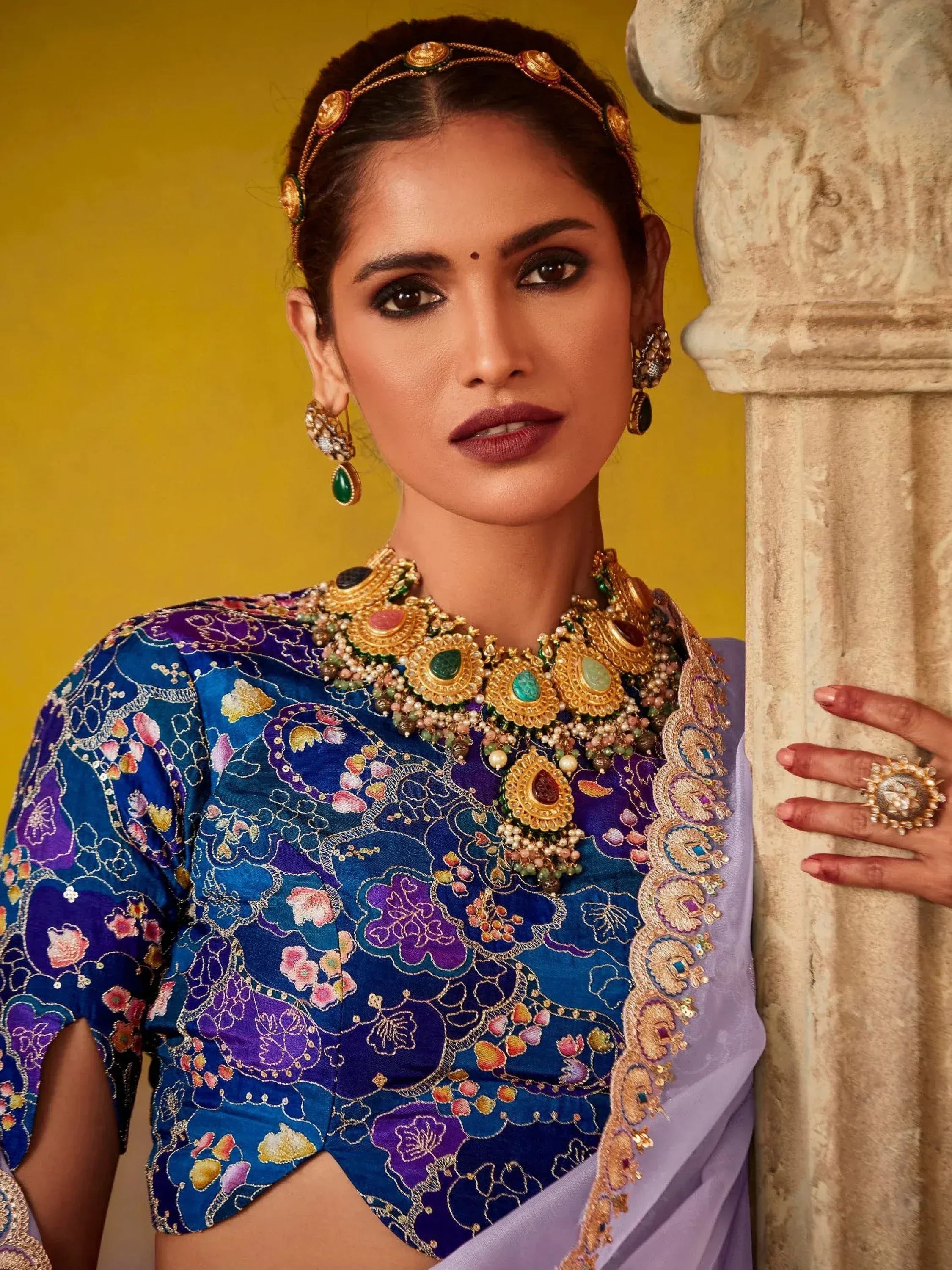 Woman in embroidered blue and purple ethnic blouse with gold jewelry, styled for Indian festive wear