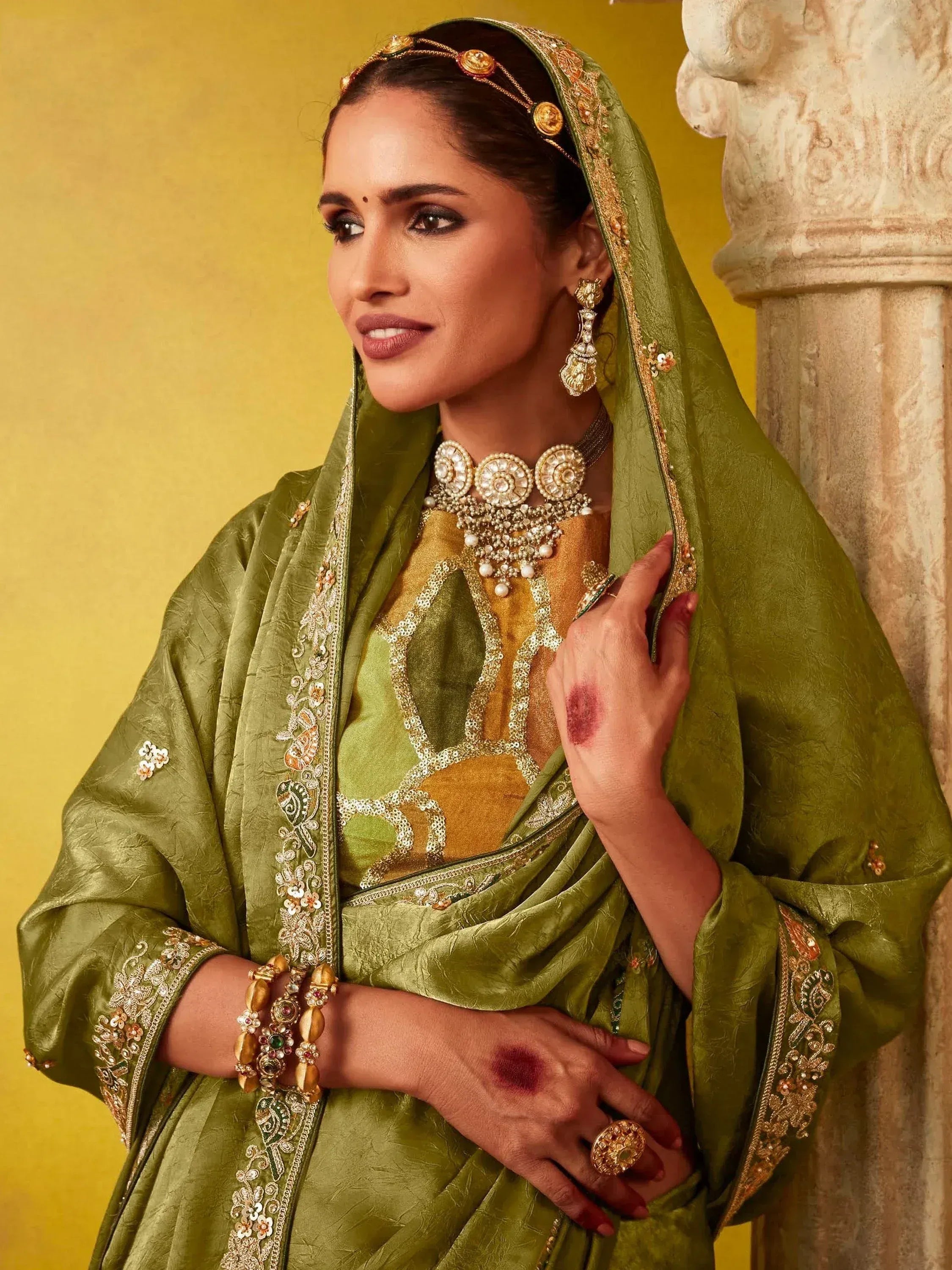 Elegant green Indian ethnic saree with gold embroidery, traditional jewelry, and henna designs for festive occasions