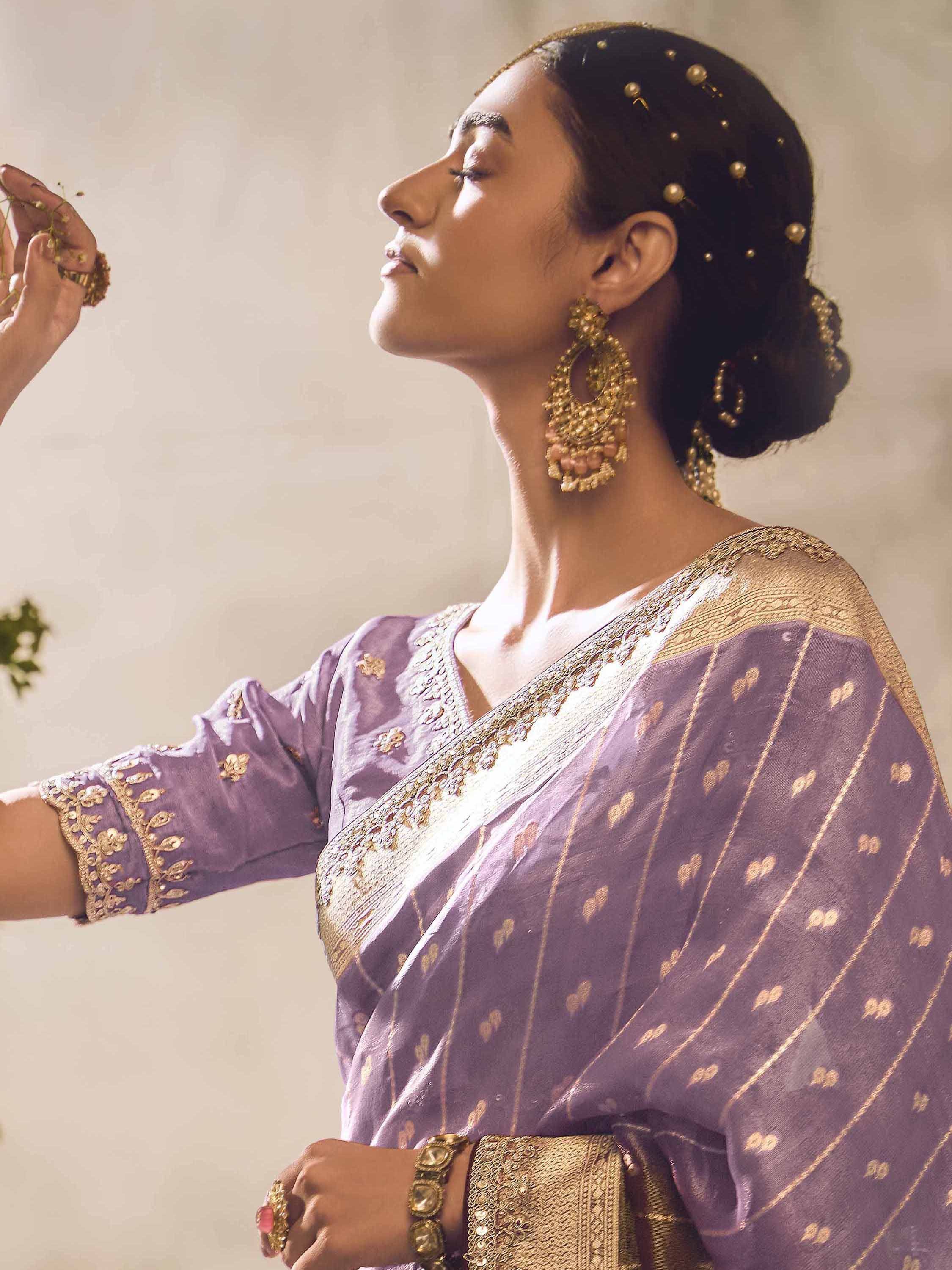 Woman in lavender ethnic saree with gold embroidery and traditional jewelry, perfect for Indian occasions.