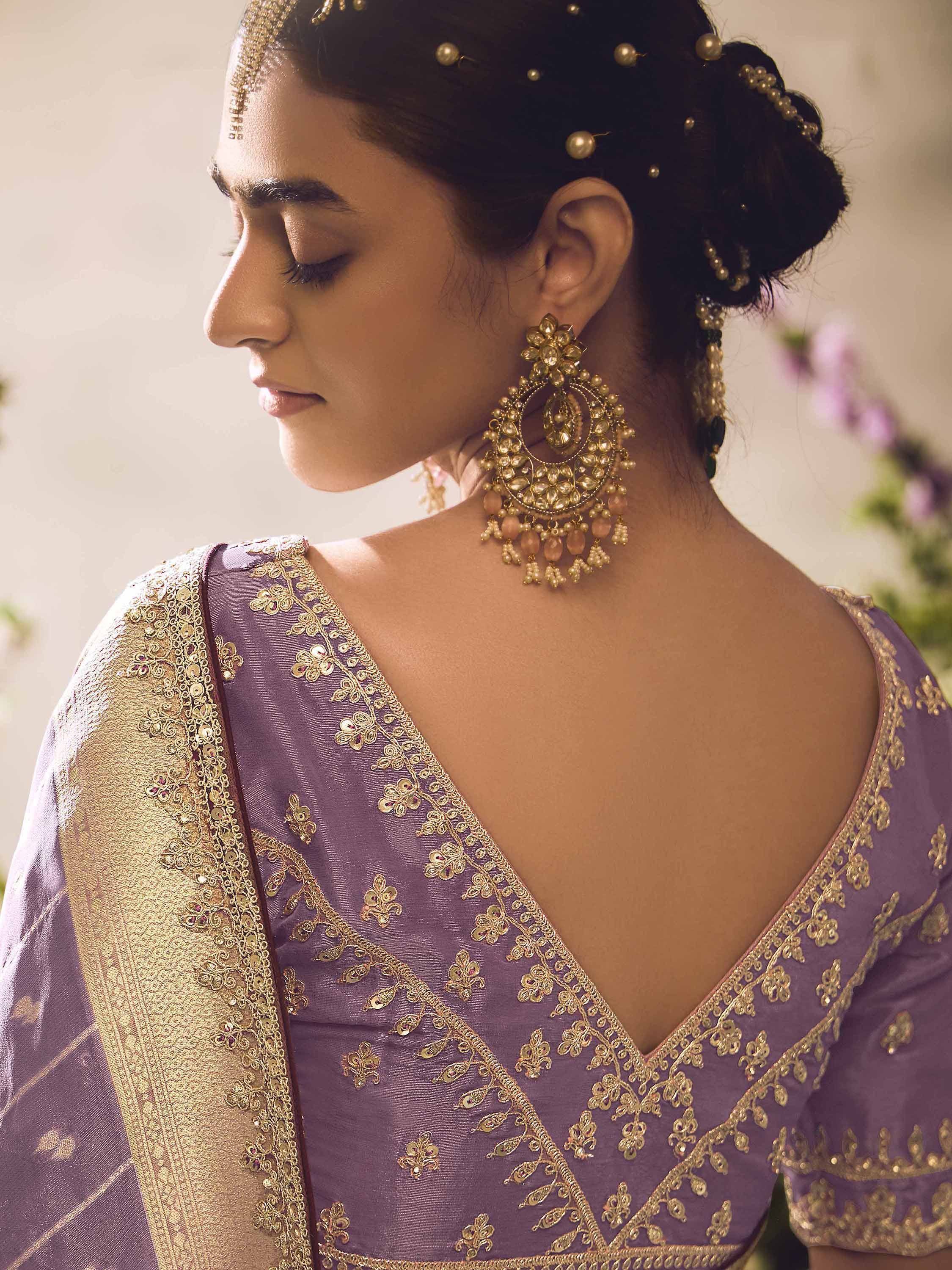 Purple embroidered saree with gold detailing, traditional Indian ethnic wear, designer jewelry, and bridal hairstyle