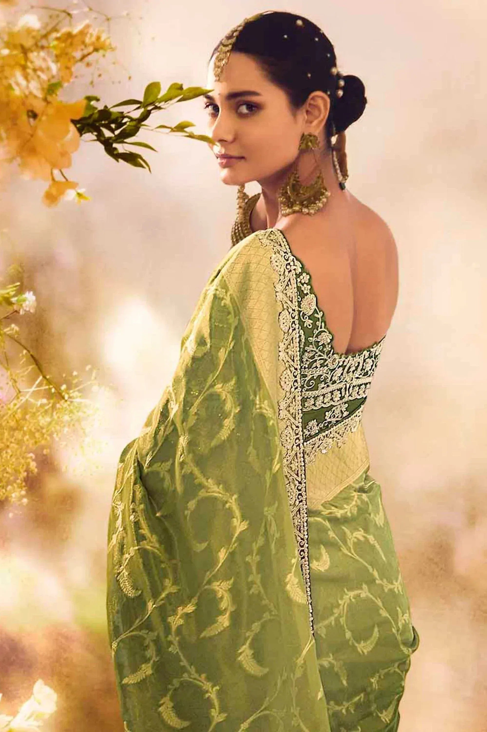 Elegant green designer saree with gold embroidery and backless blouse, perfect for Indian ethnic occasions.