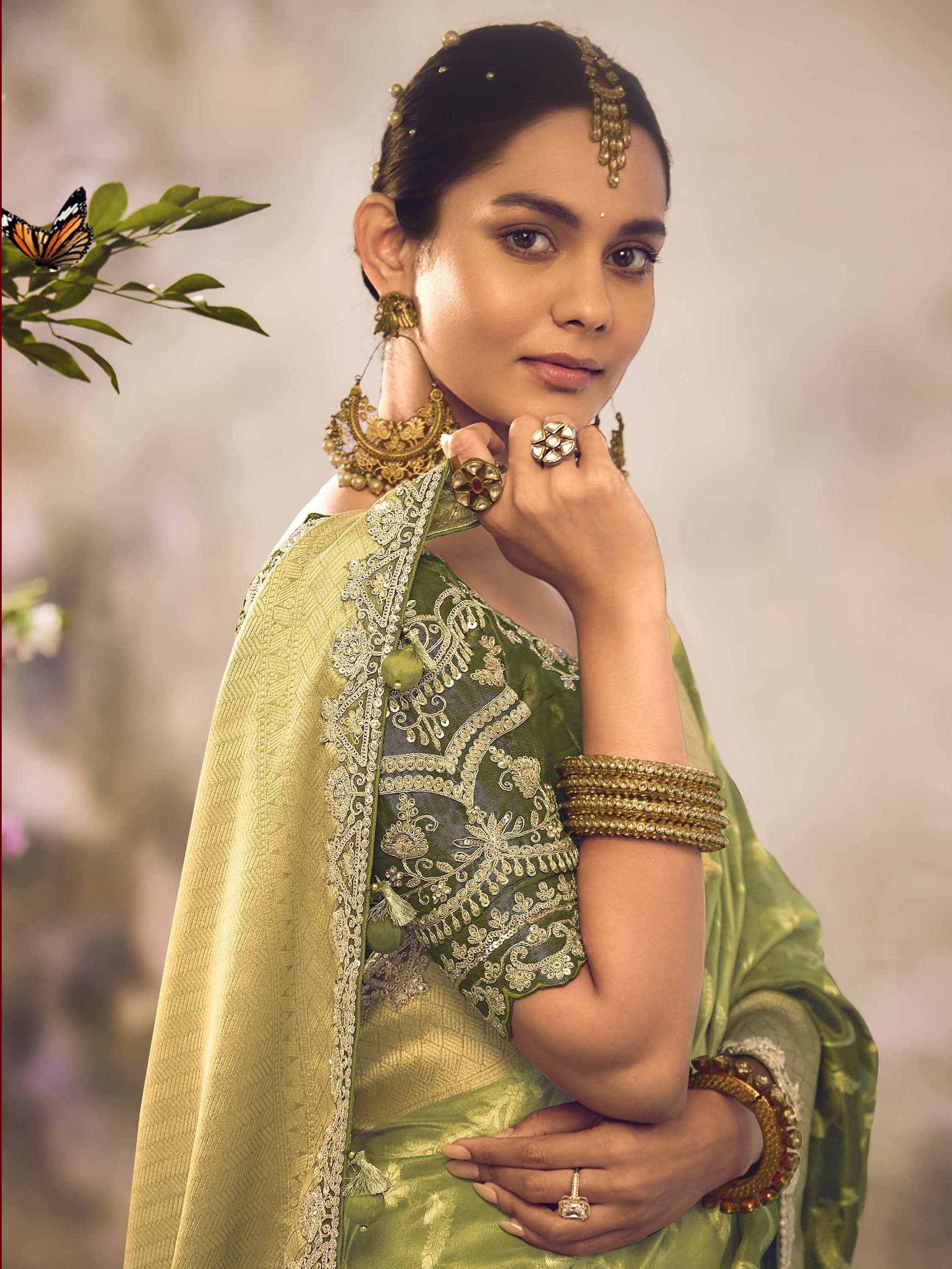 Woman in green embroidered saree with gold jewelry and traditional Indian headpiece
