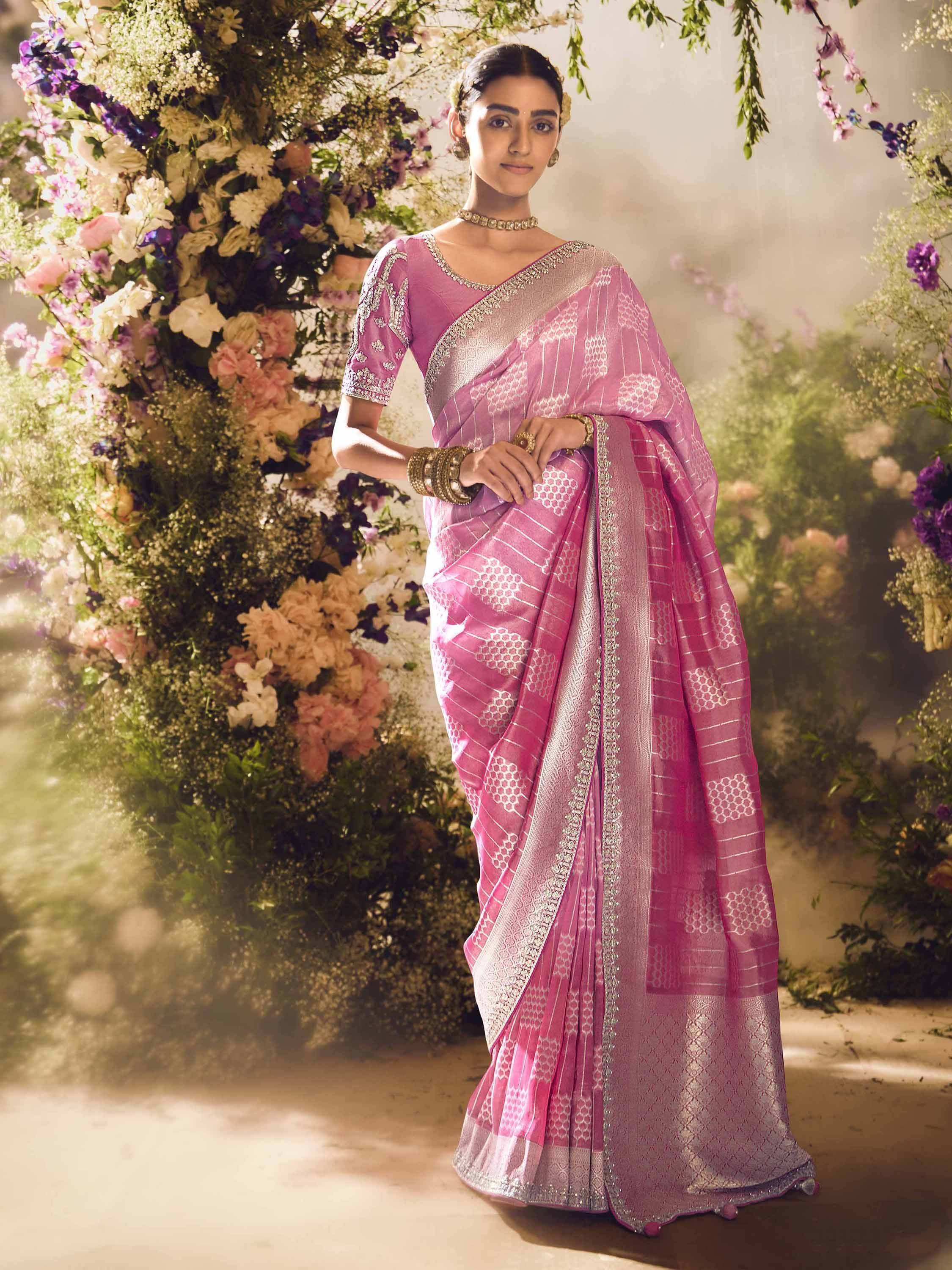 Pink embroidered saree with silver border, styled with floral backdrop for Indian ethnic wear