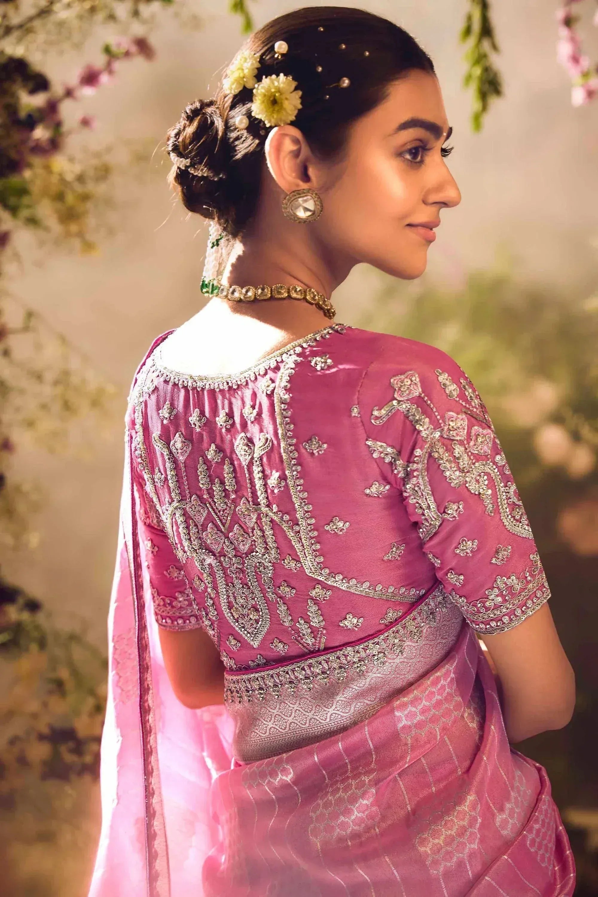 Pink embroidered saree with detailed back design, floral hair accessories, and traditional jewelry for Indian ethnic wear