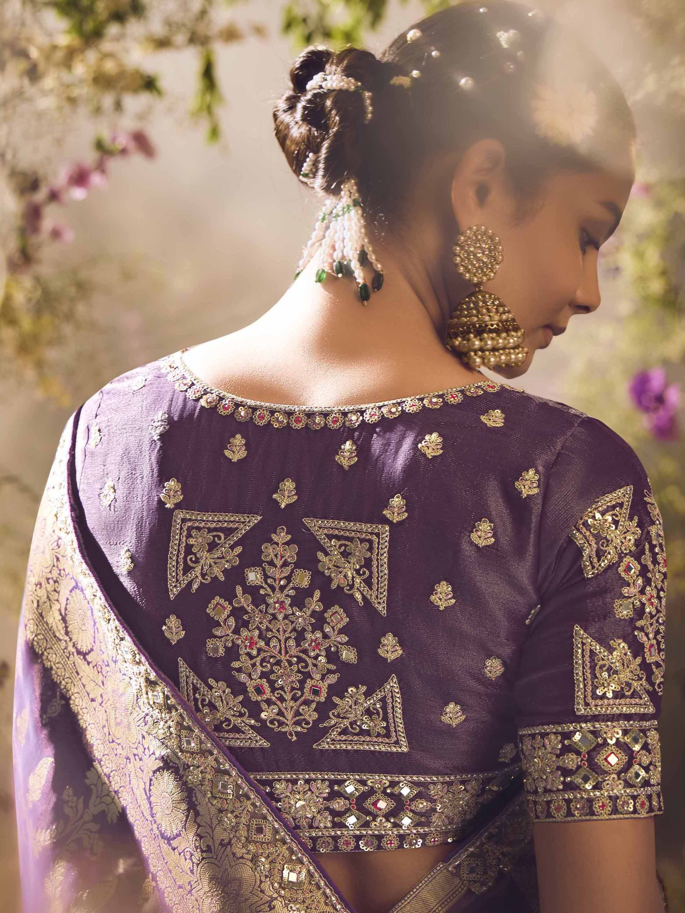 Purple designer saree blouse with gold embroidery and mirror work, paired with traditional Indian jewelry.