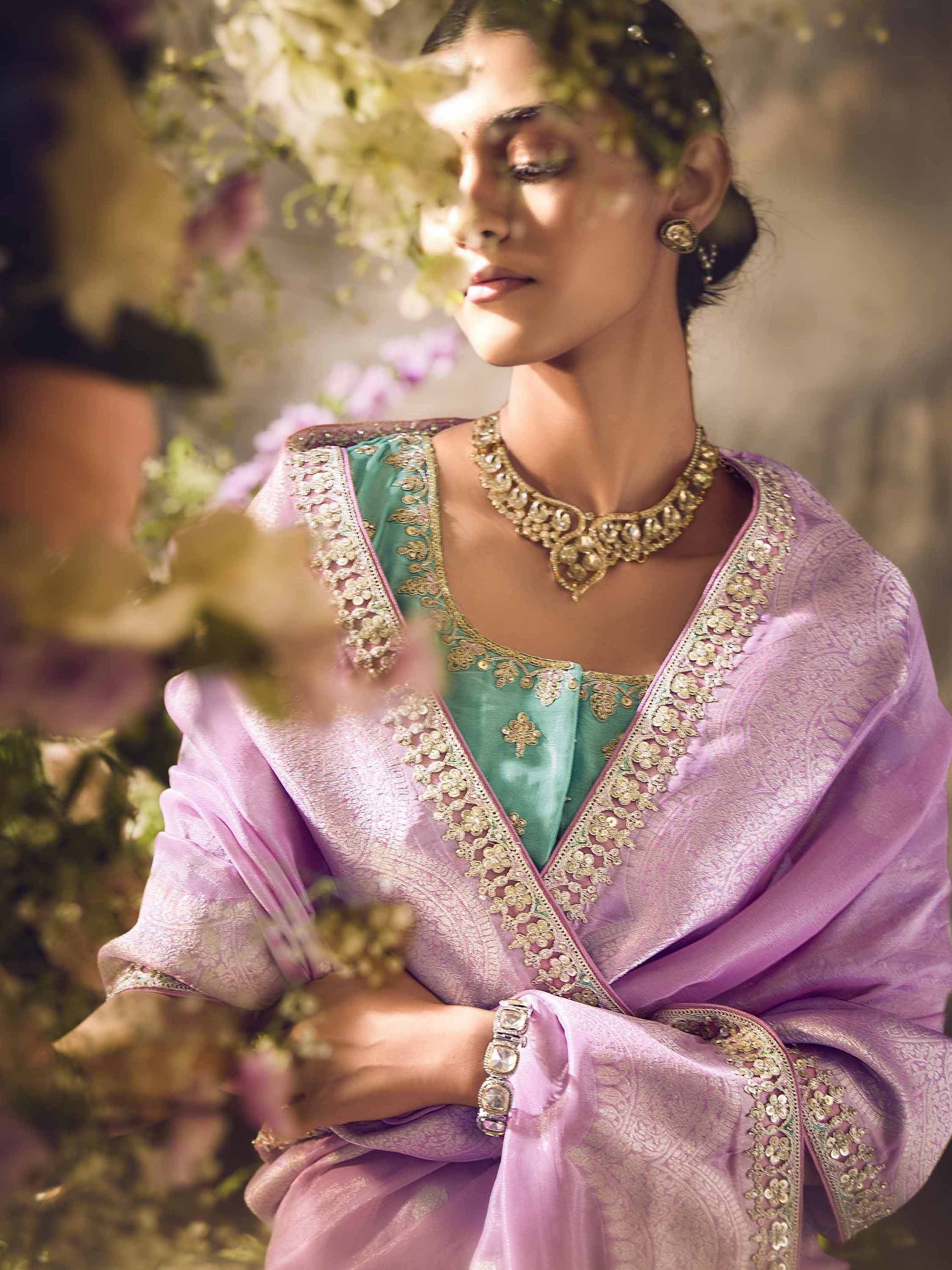 Elegant Indian ethnic wear with lavender dupatta and teal blouse, adorned with gold embroidery and jewelry