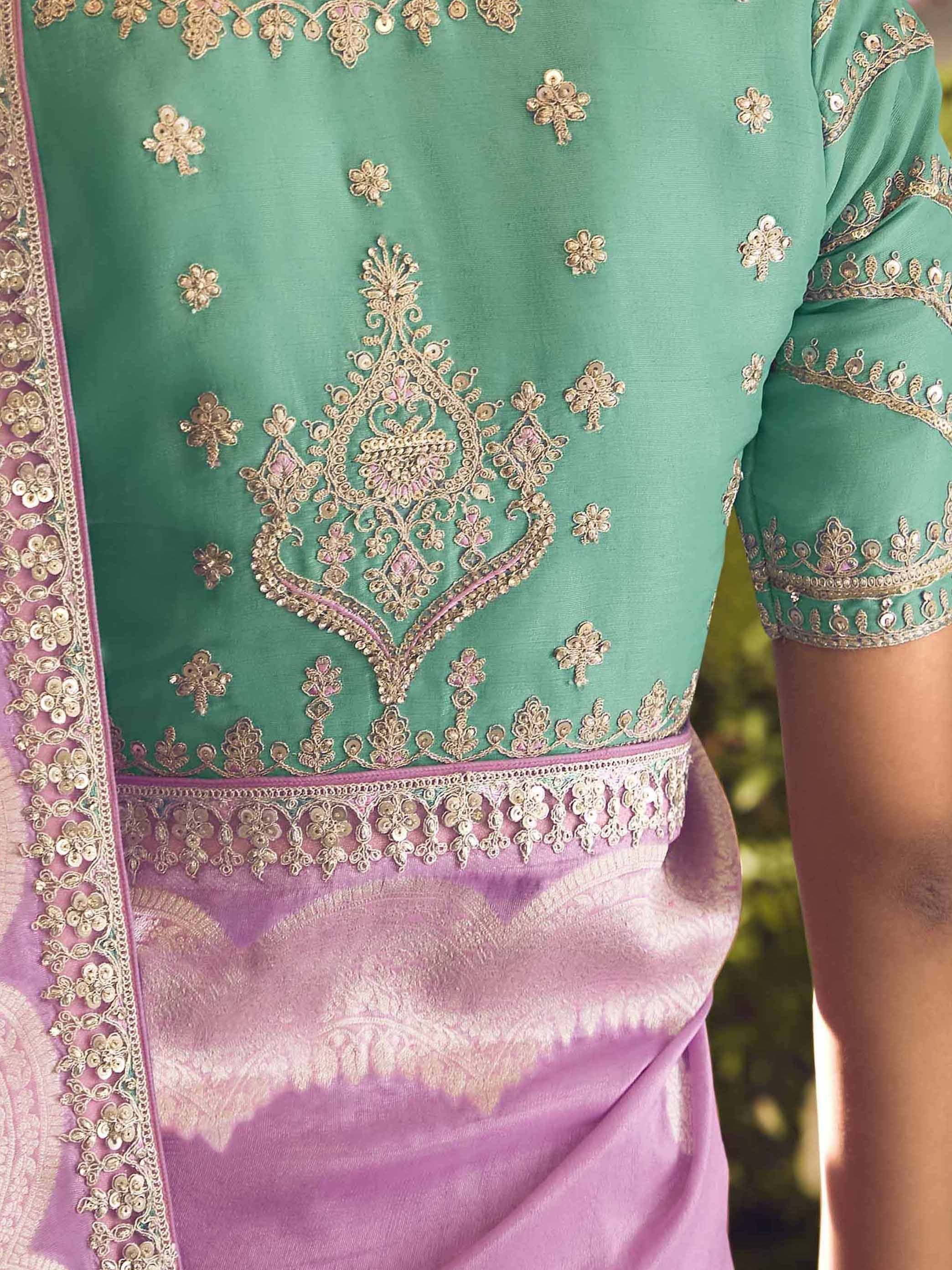 Green embroidered designer salwar kameez with pink dupatta, featuring intricate gold zari work and floral motifs.