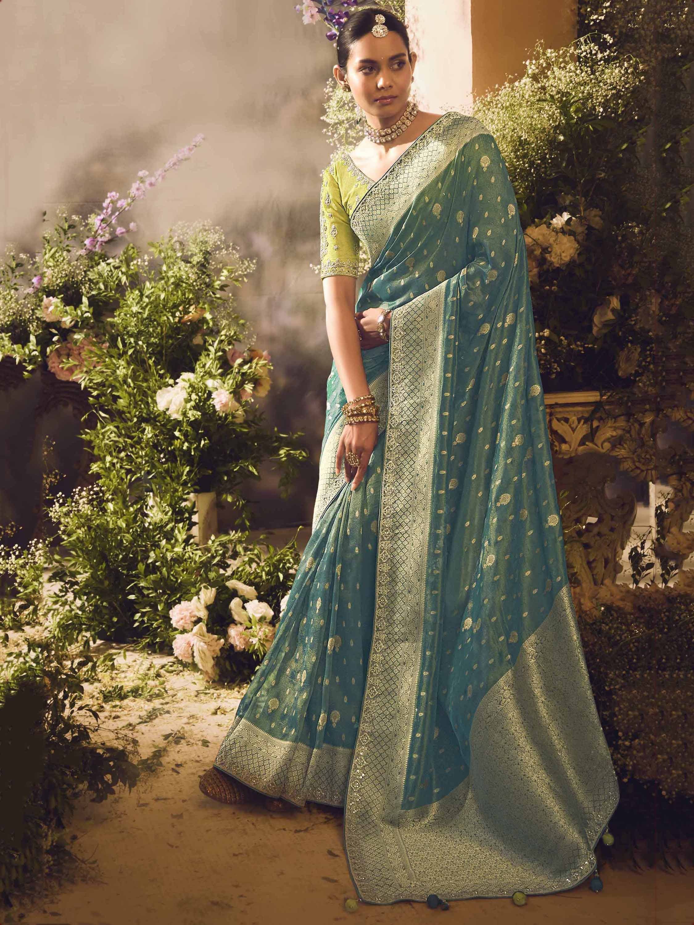 Teal and gold embroidered saree with matching blouse, styled with traditional jewelry for Indian ethnic wear.