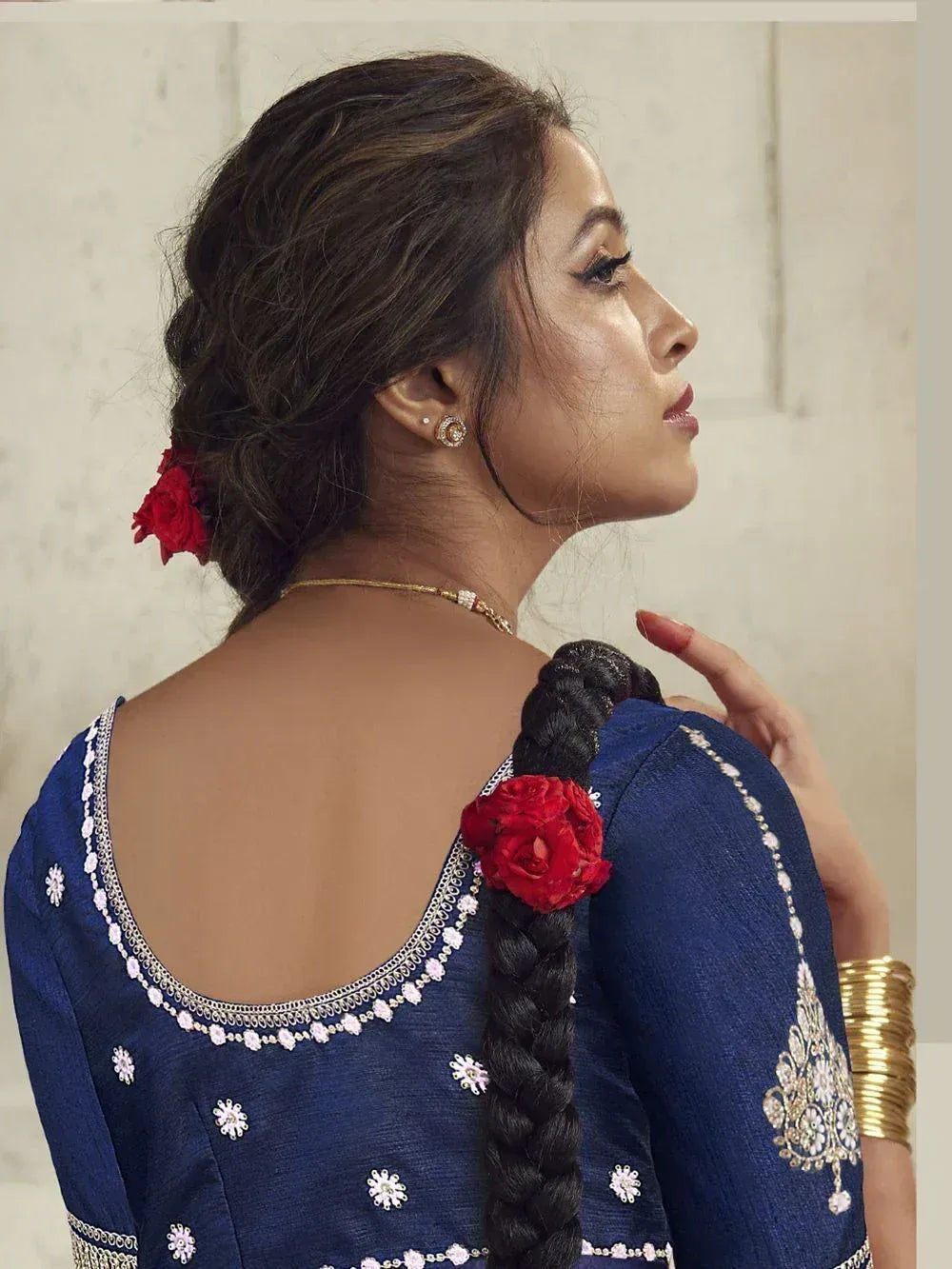 Blue embroidered ethnic blouse with open back, floral details, and red rose in braid