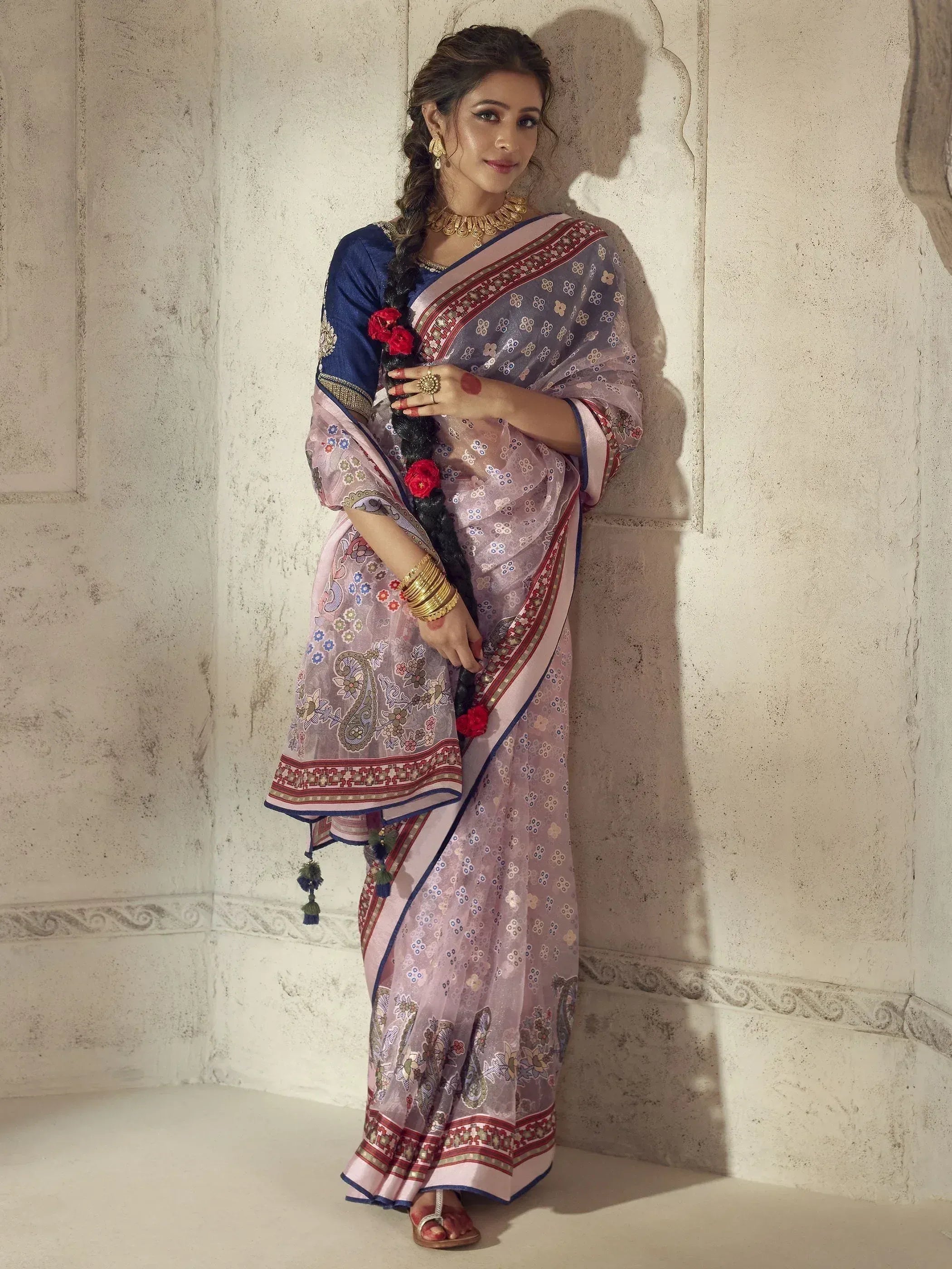 Woman in elegant pink and blue printed saree with gold jewelry, styled for Indian ethnic wear occasions.