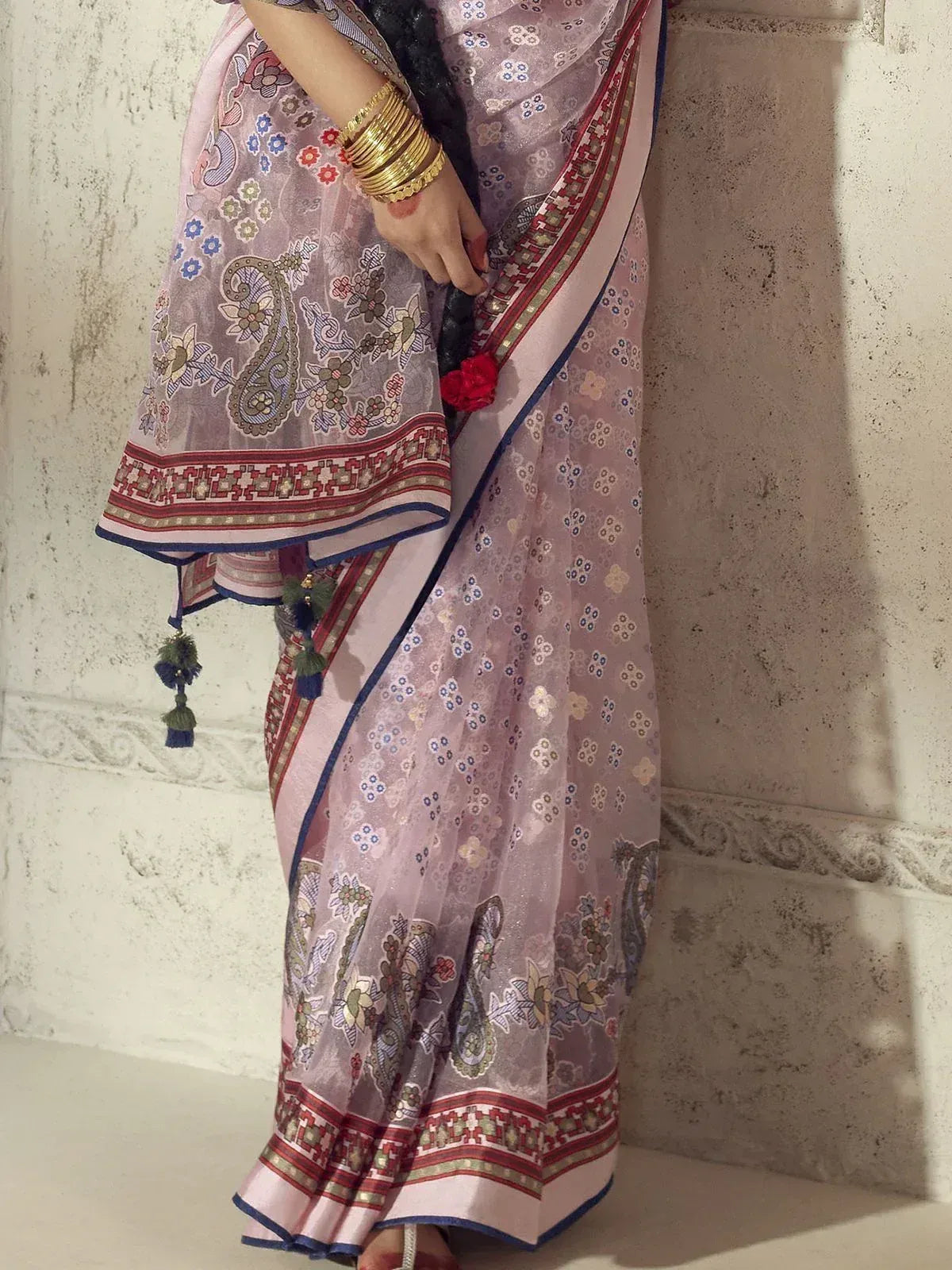Pink floral printed saree with paisley border and tassels, styled with gold bangles for ethnic wear