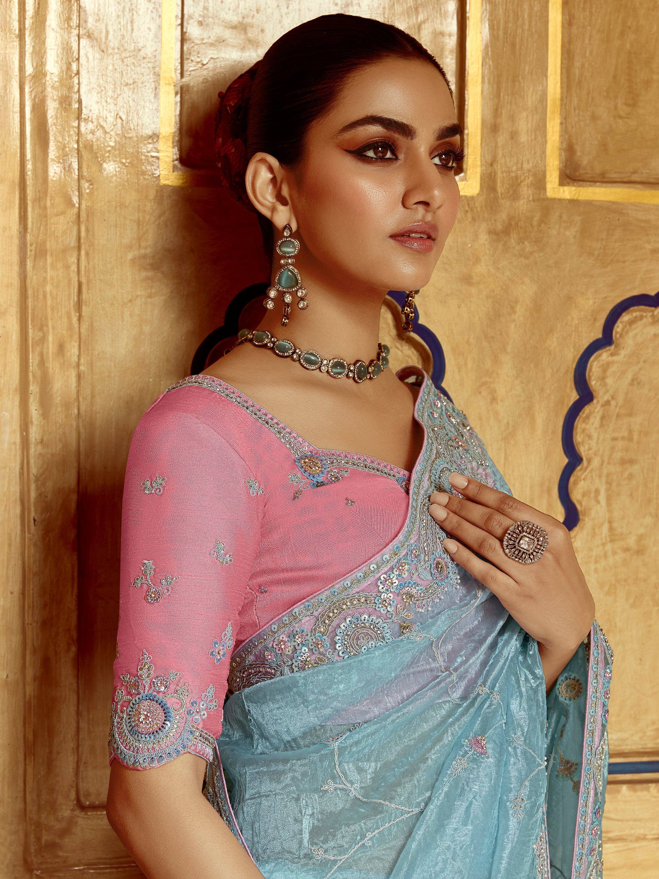 Elegant woman in pink and blue embroidered saree with matching jewelry, showcasing ethnic wear.