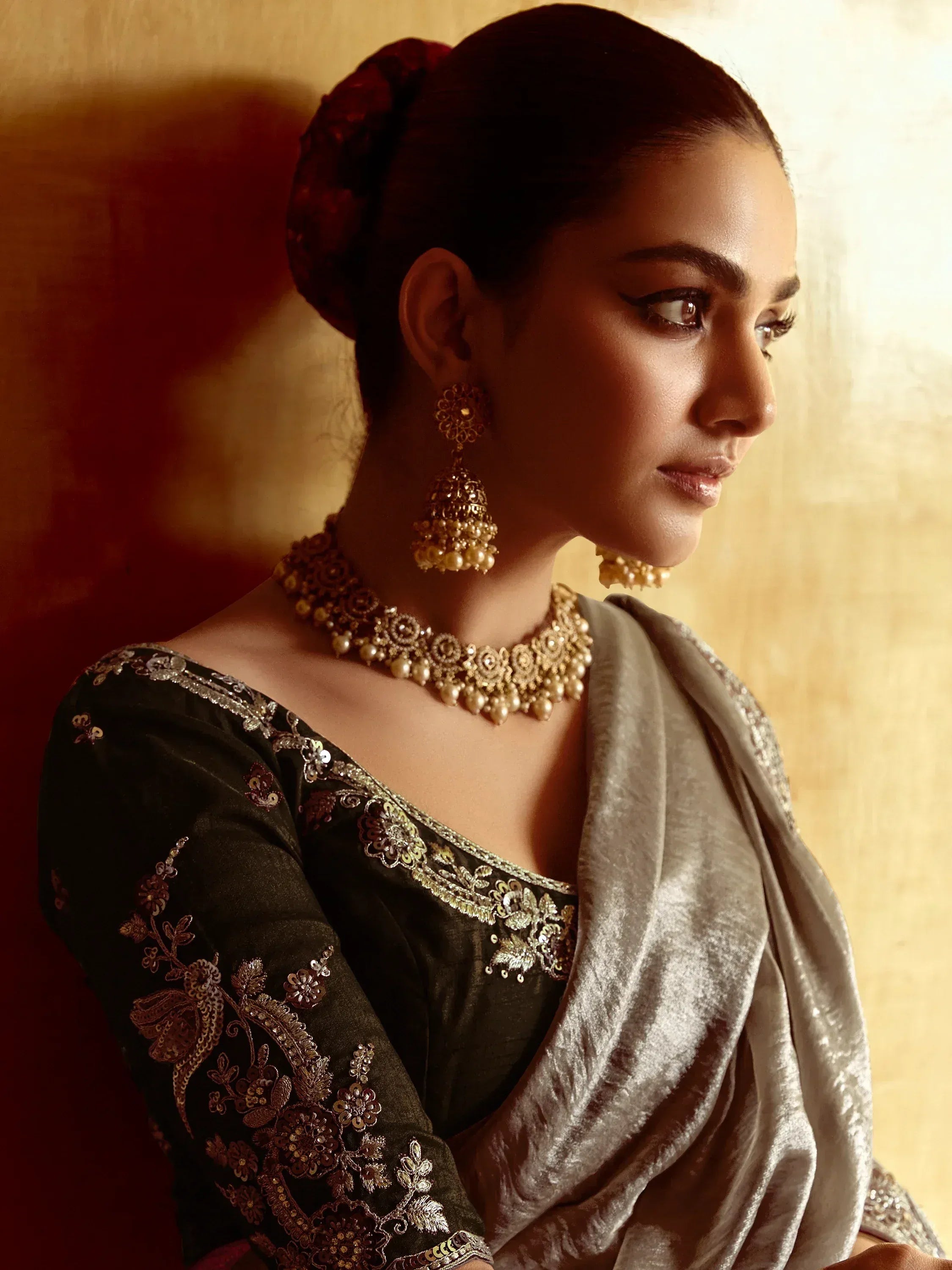 Elegant woman in embroidered ethnic gown with gold jewelry and velvet dupatta