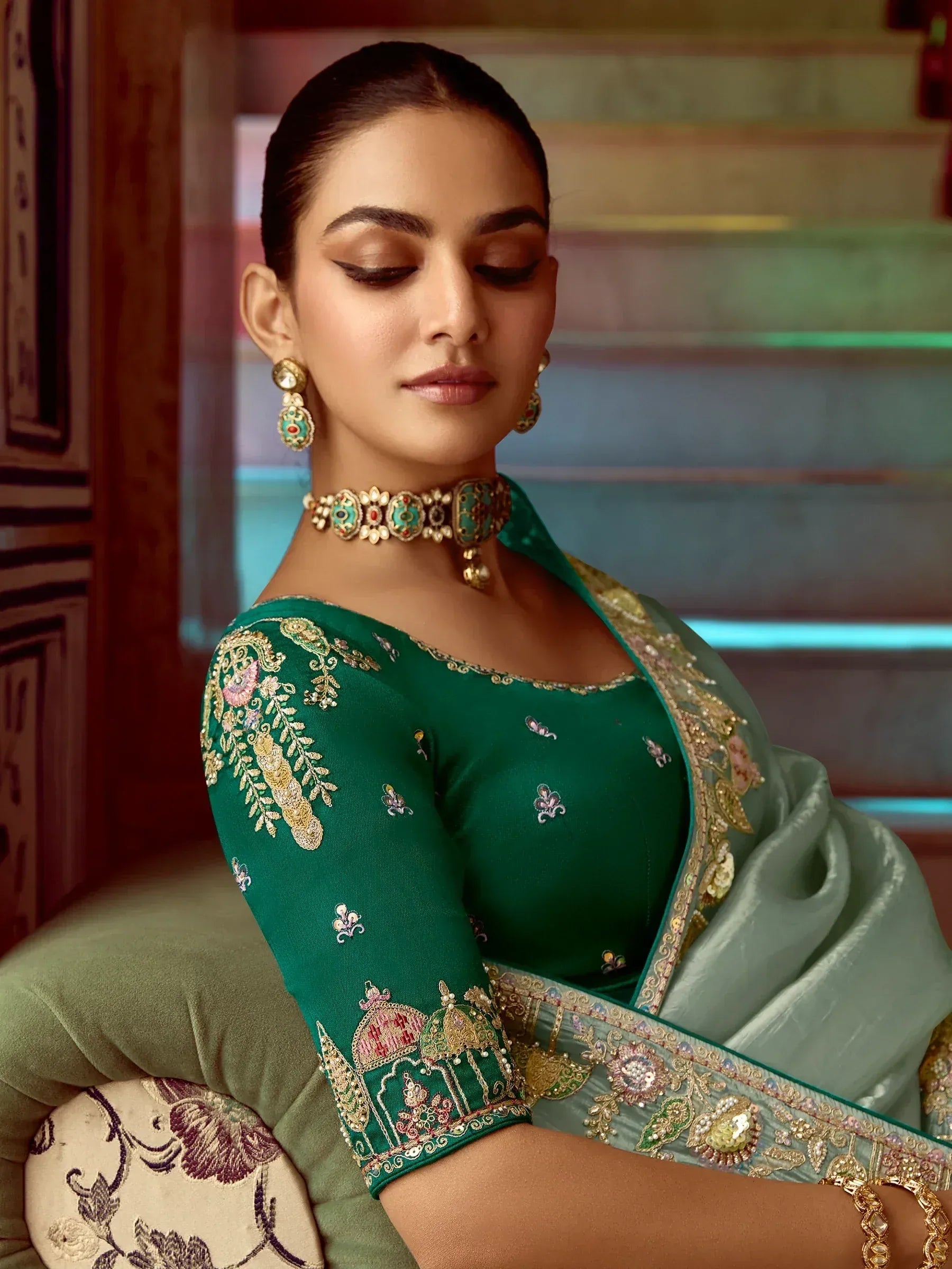 Elegant green embroidered saree with floral motifs and gold detailing, paired with traditional jewelry.